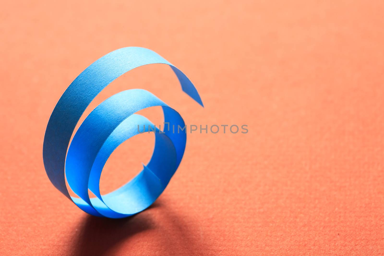 One blue spiral made from paper on red background