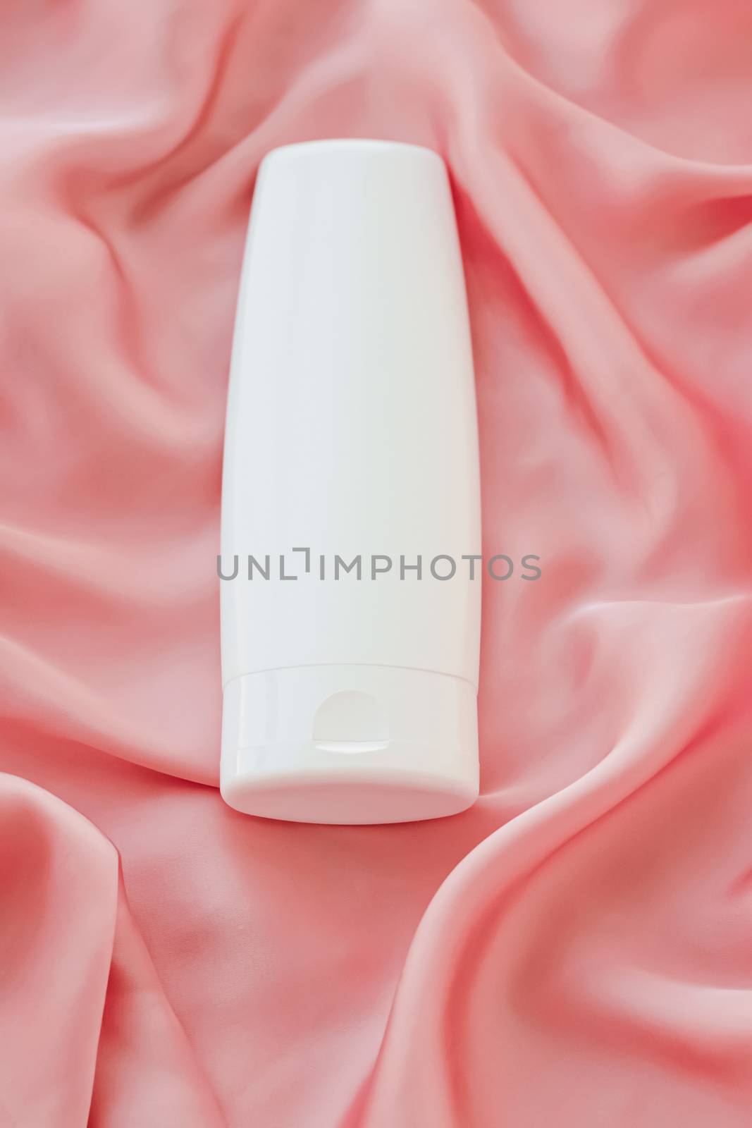 Blank label cosmetic container bottle as product mockup on pink silk background by Anneleven