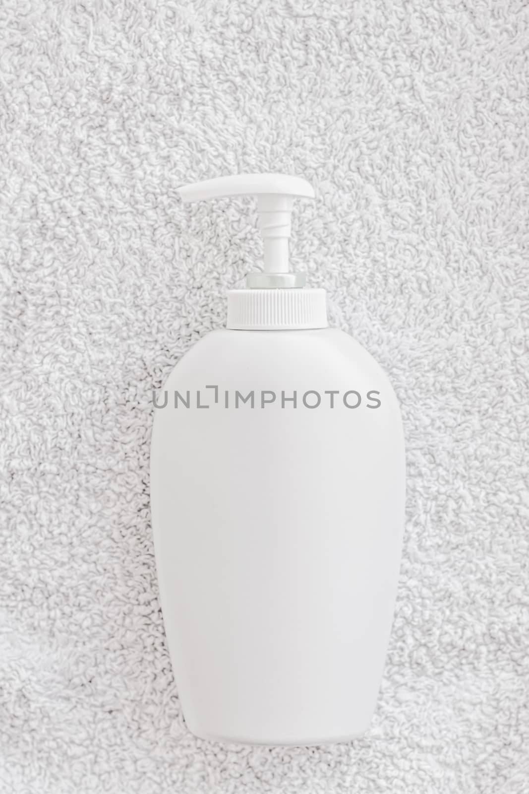 Blank label cosmetic container bottle as product mockup on white towel background, hygiene and healthcare