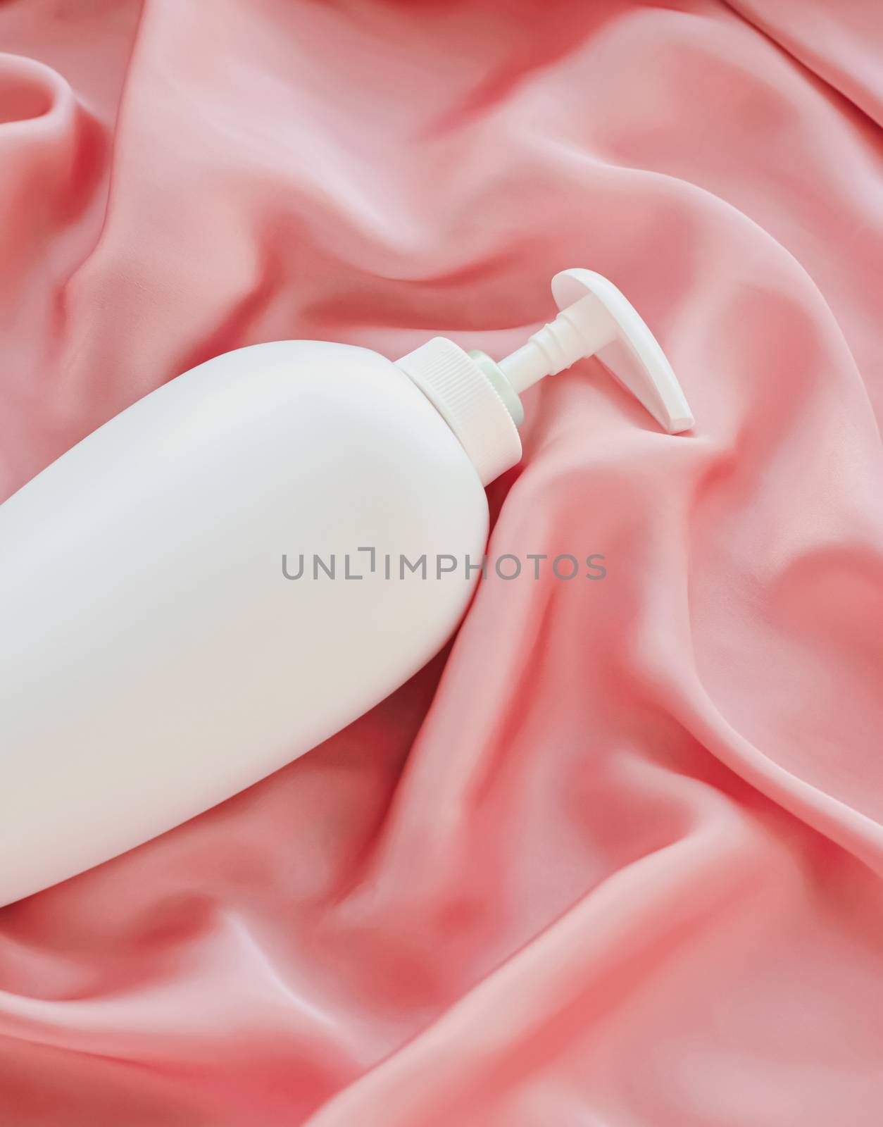 Blank label cosmetic container bottle as product mockup on pink silk background by Anneleven