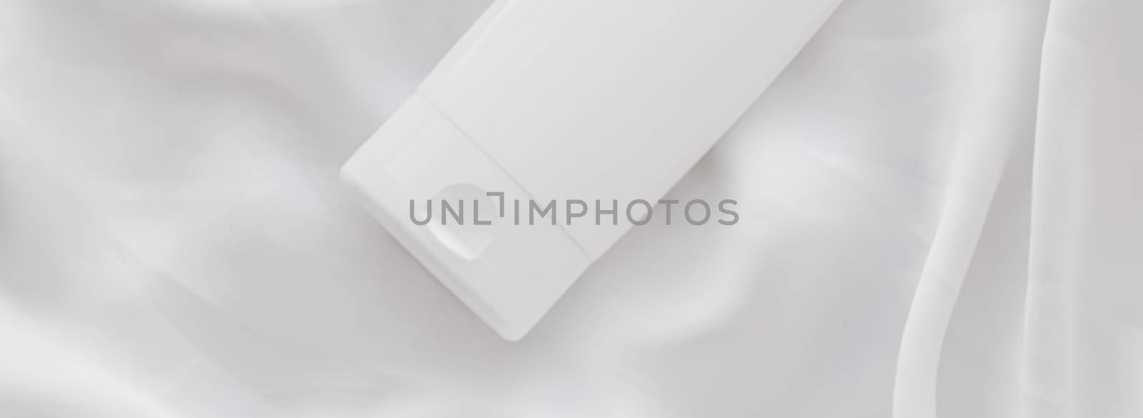 Blank label cosmetic container bottle as product mockup on white silk background by Anneleven