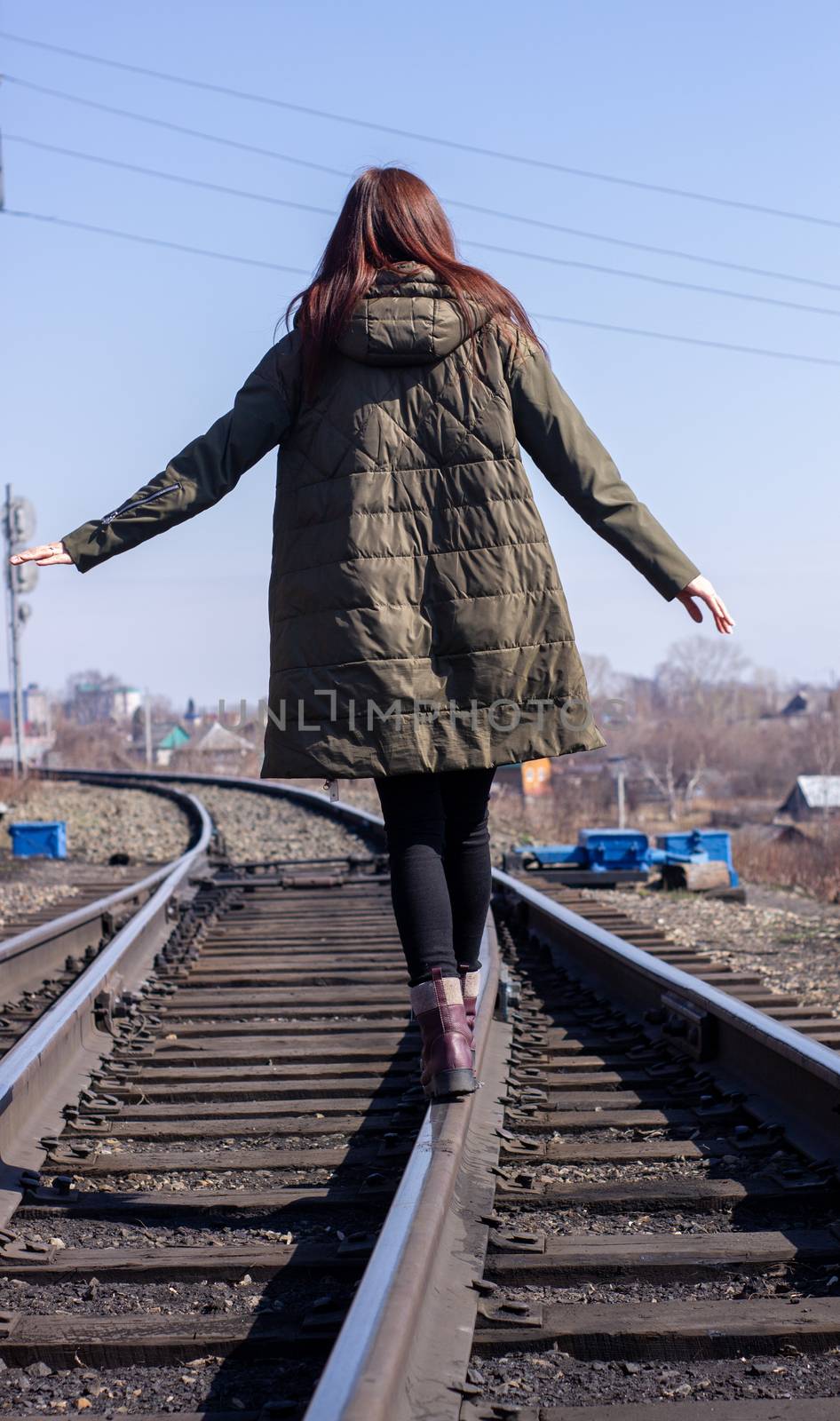 The girl is walking on the railway in front. Rear view. by AnatoliiFoto