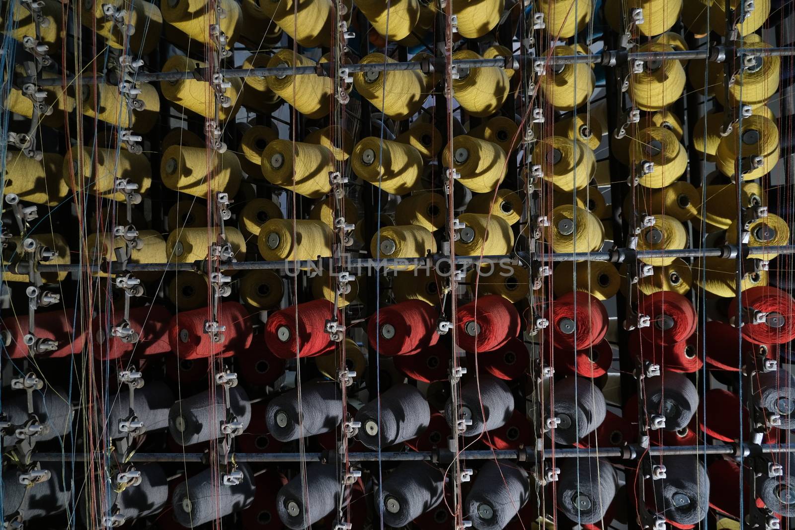 Thread spools of an industrial weaving loom for fabrication of fabrics.