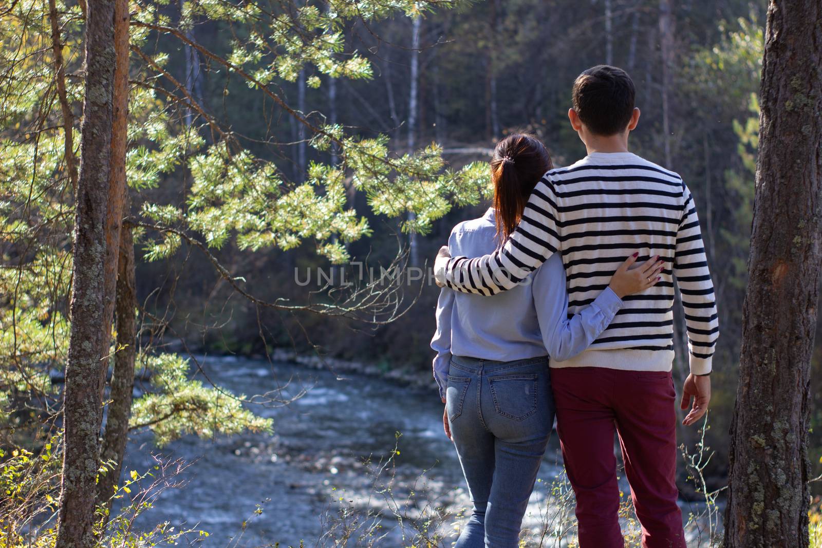 A guy and a girl are on the outdoors looking in front. Rear view by AnatoliiFoto