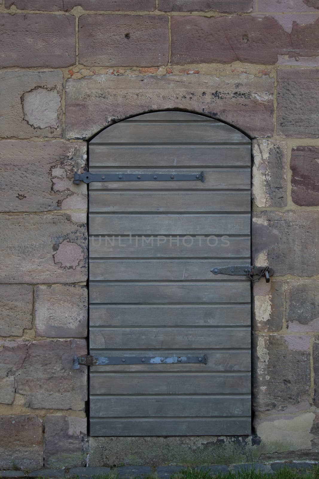 A wooden door against a stone wall. Walk near the Castle by AnatoliiFoto