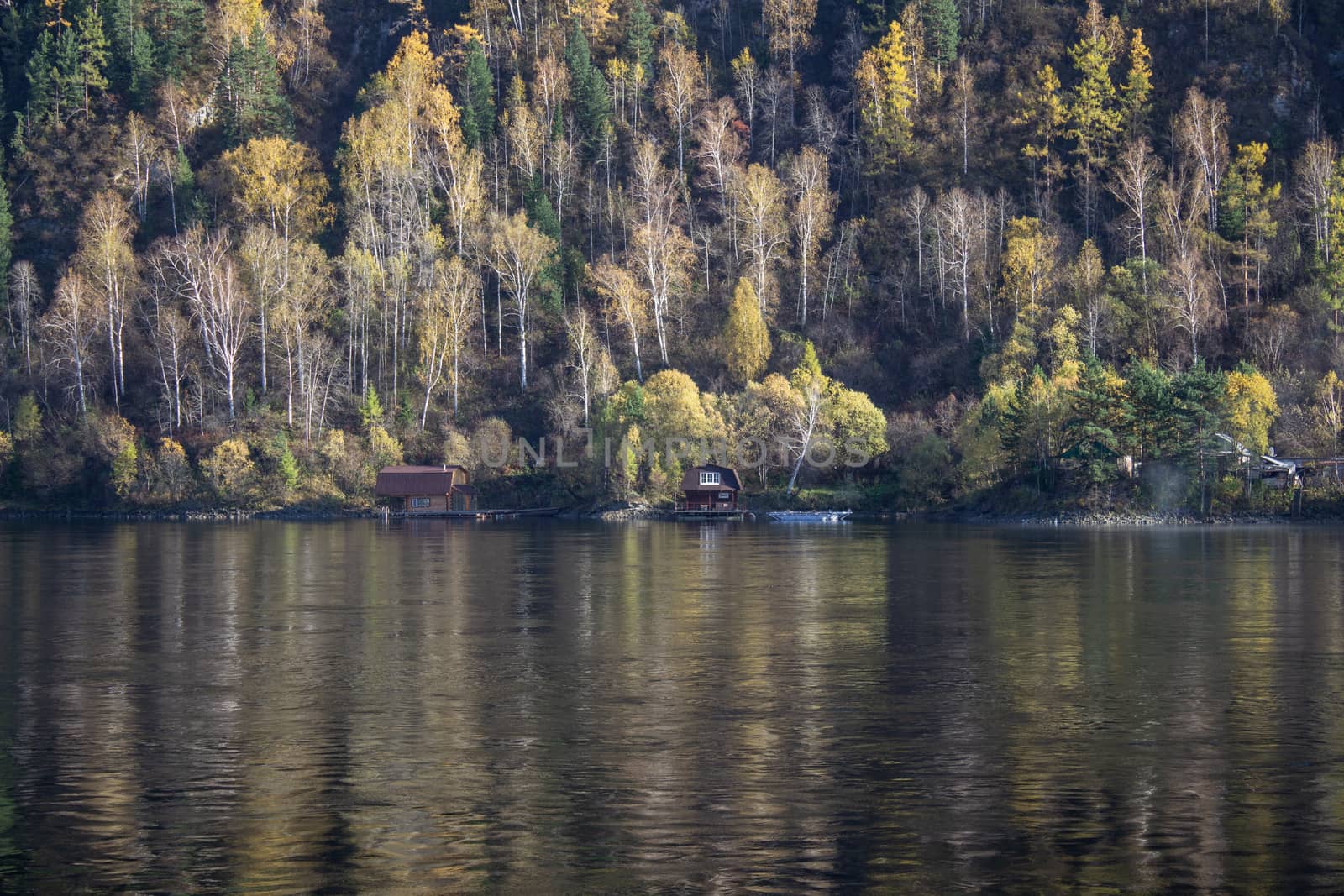 A wide river that lies in the mountain valley. Mountains near the river are covered with forests.