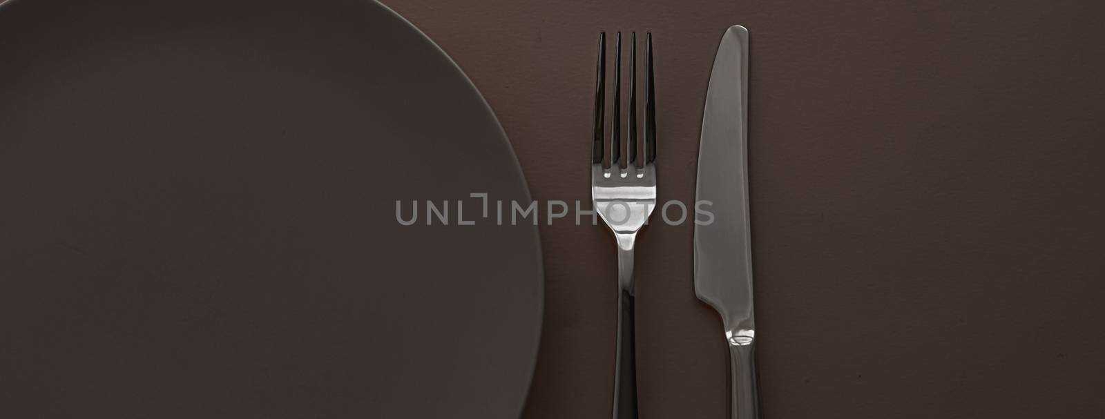 Empty plate and cutlery as mockup set on dark brown background, top tableware for chef table decor and menu branding by Anneleven