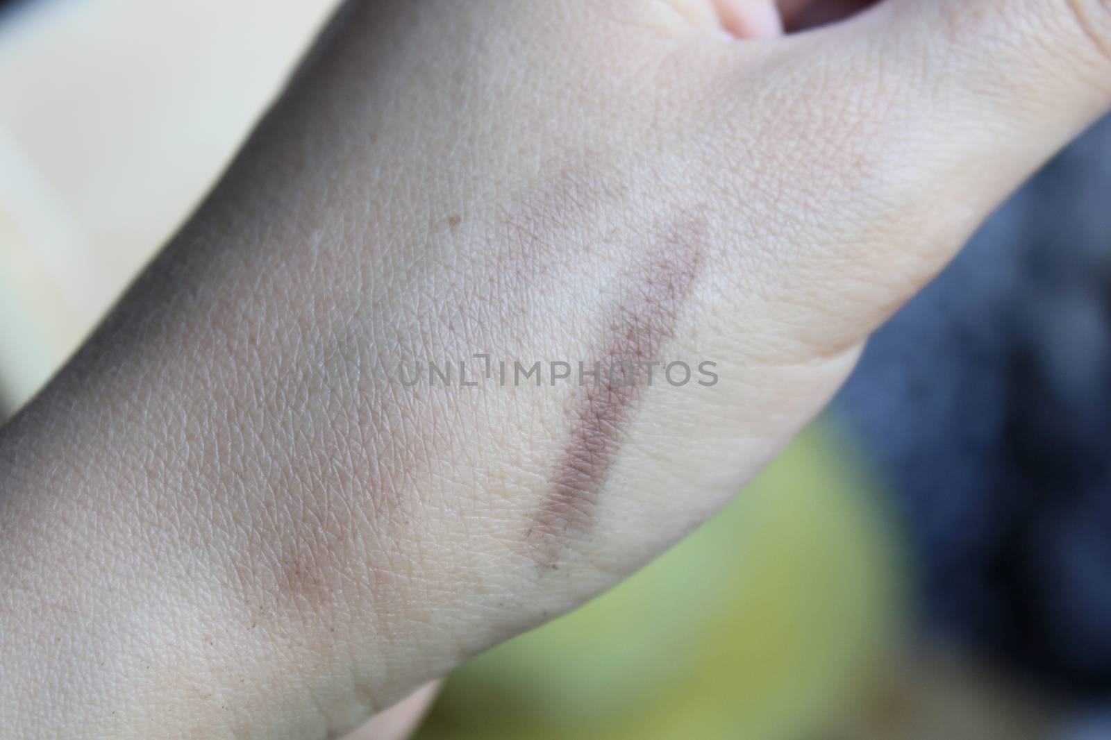 Swatches of shimmer palette eyeshadows on a woman's fingers. Wood background