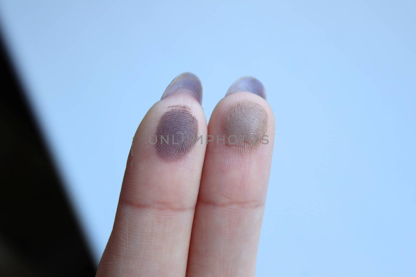 Swatches of shimmer palette eyeshadows on a woman's fingers. Wood background