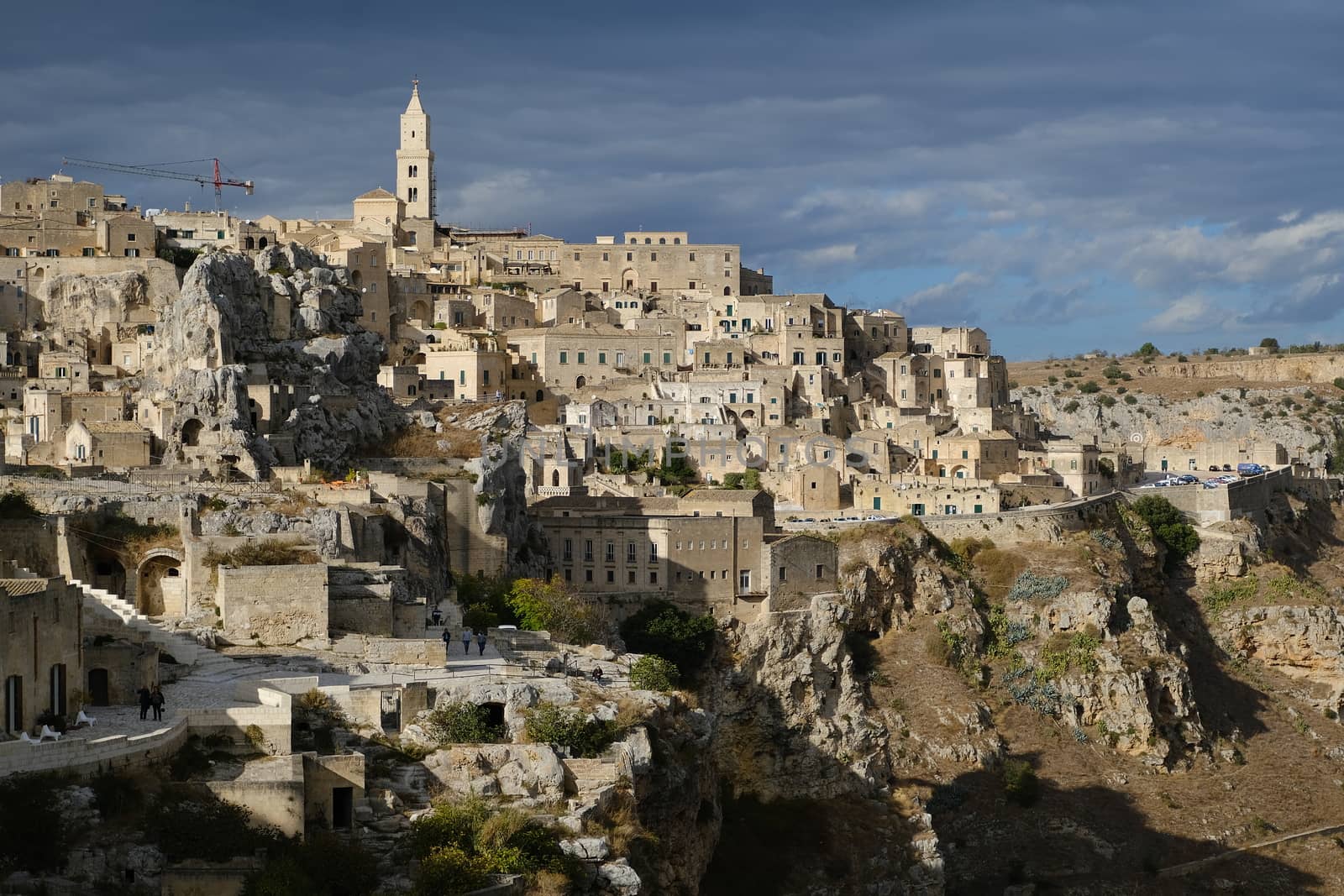 Panorama of the Sassi of Matera with houses in tuff stone. Church and bell tower at dawn with sky and clouds.