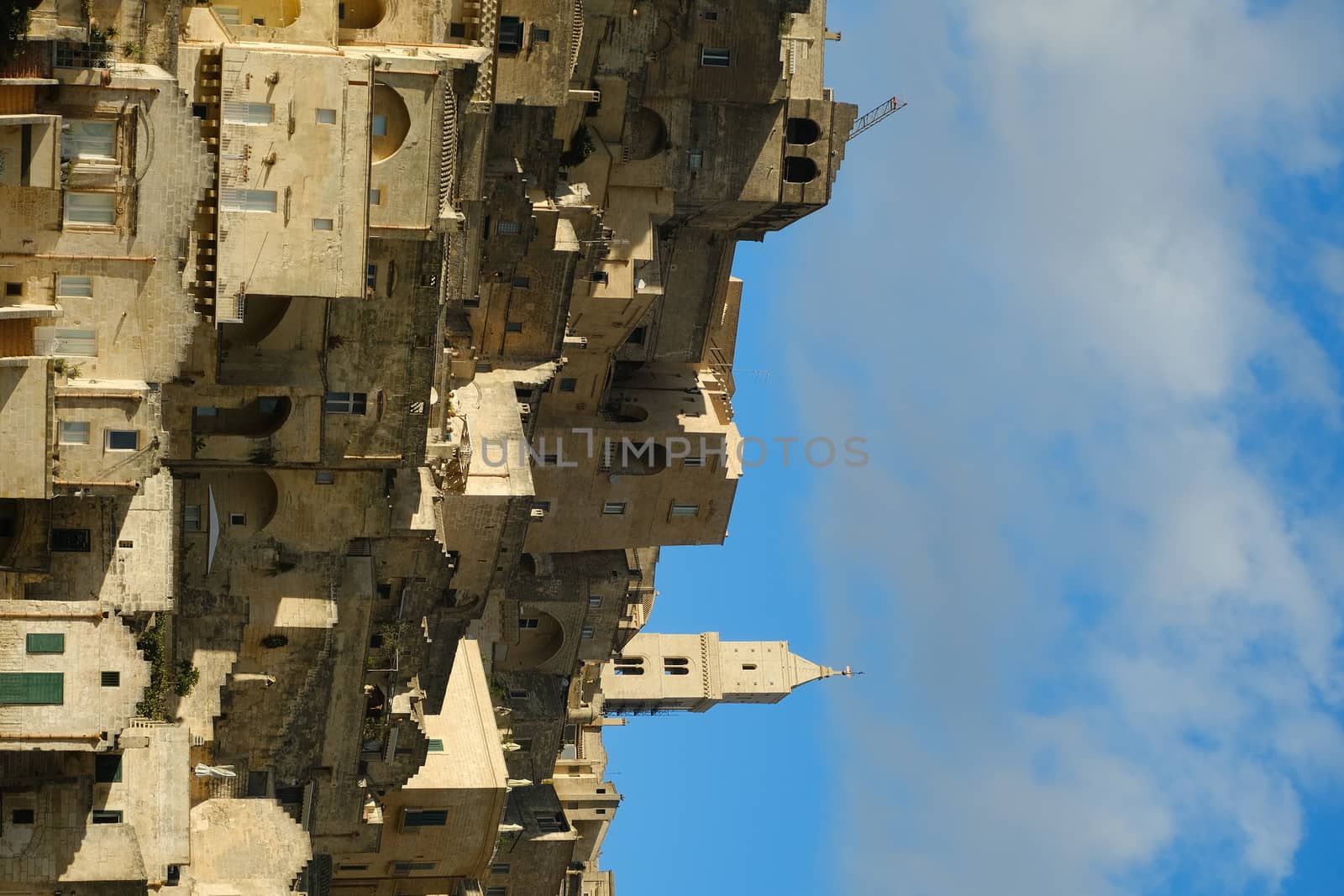 Panorama of the Sassi of Matera with houses in tuff stone. Church and bell tower at dawn with sky and clouds.