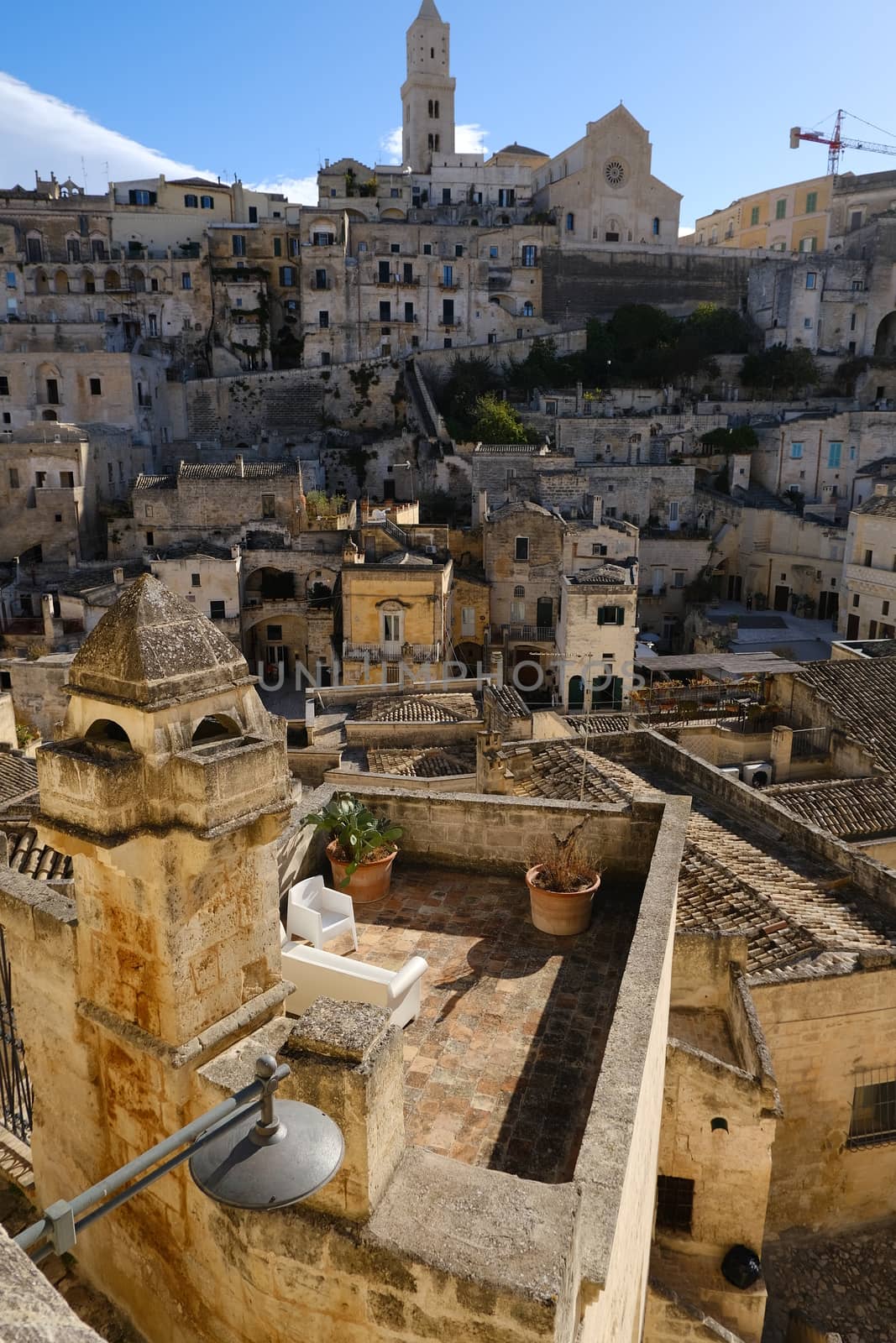 Roofs of houses in the Sassi of Matera transformed into hotels. Panoramic terrace with sofa and chair in white plastic.