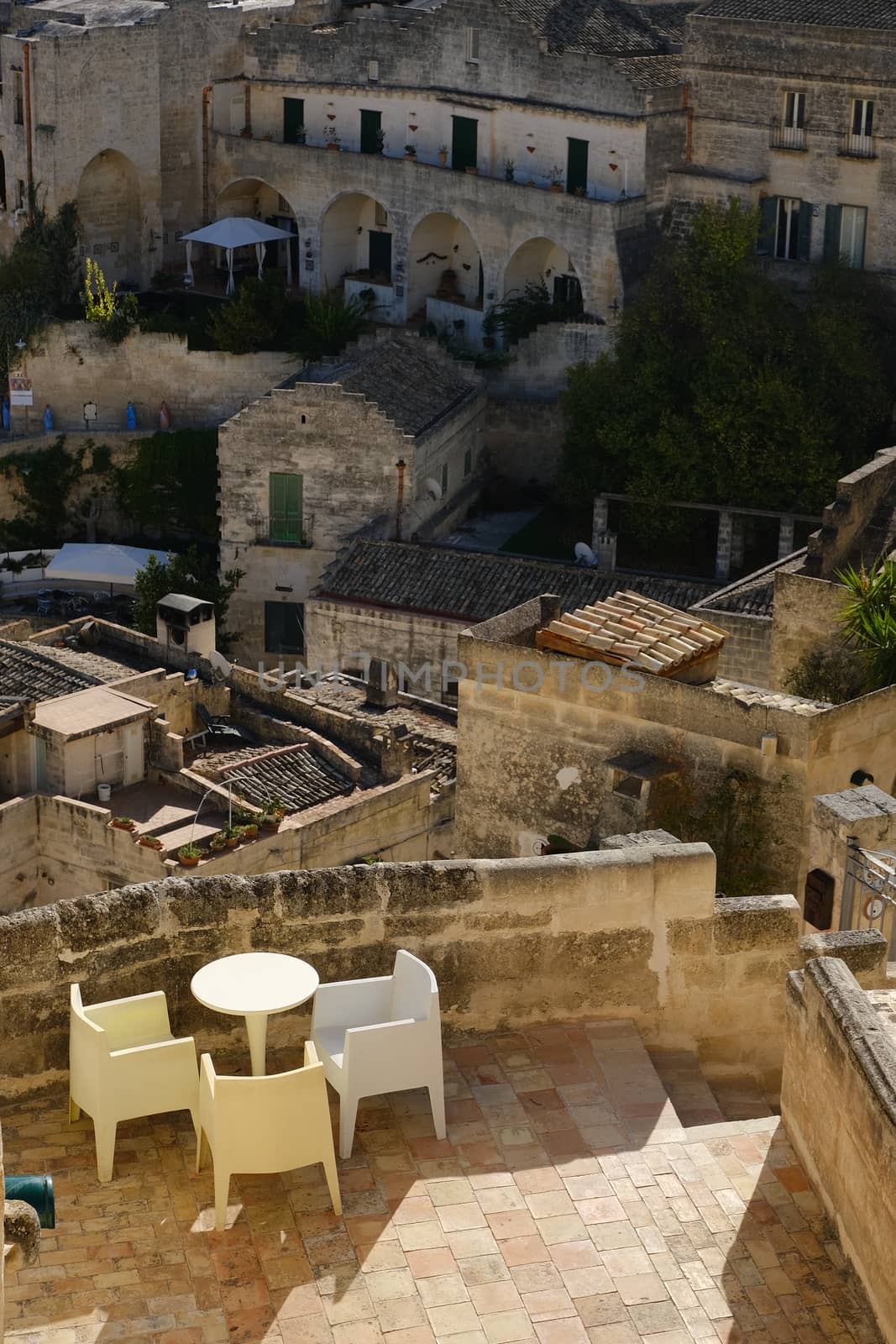 Matera, Basilicata, Italy. About 11/2019. Roofs of houses in the Sassi of Matera transformed into hotels. Panoramic terrace with sofa and chair in white plastic.