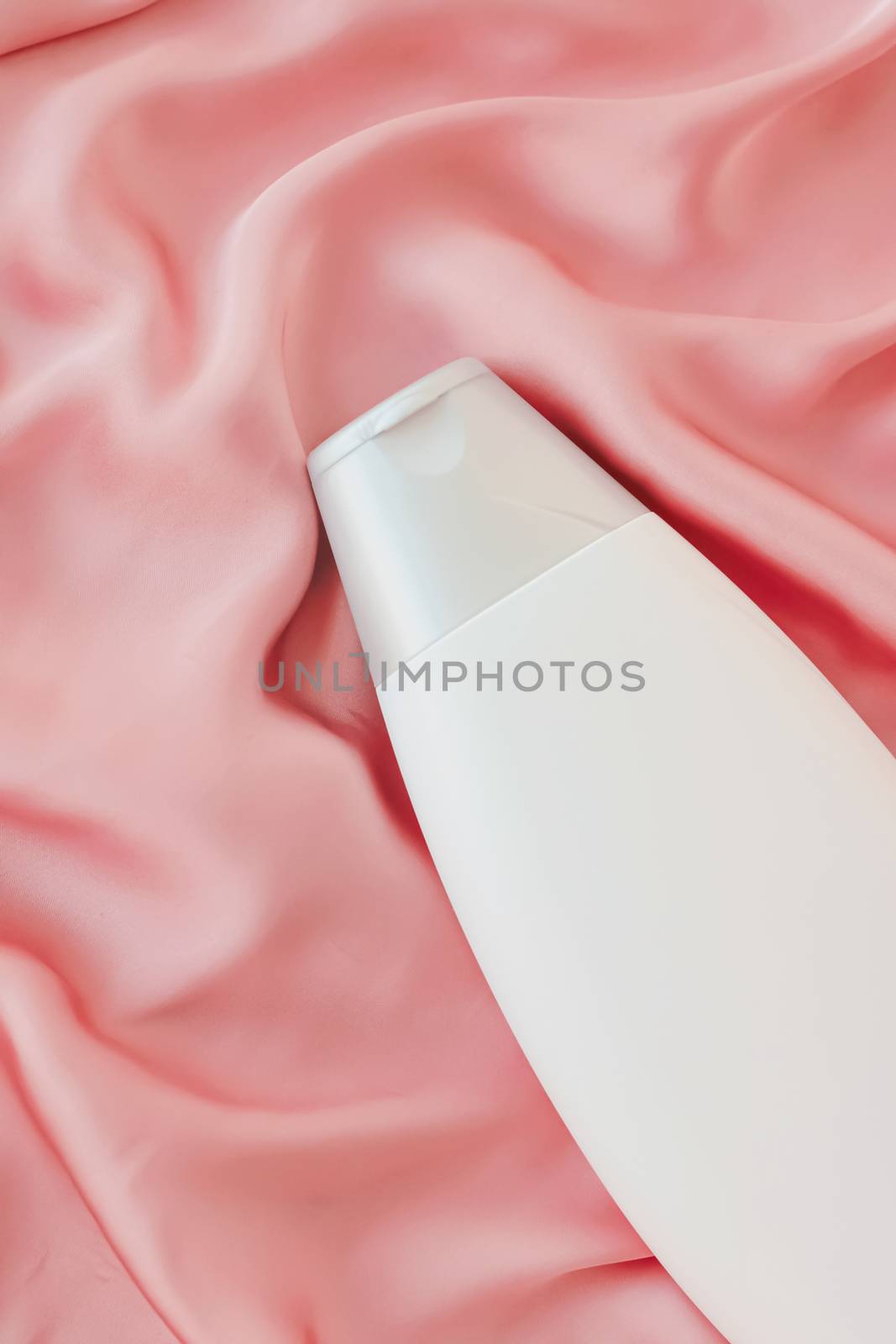 Blank label cosmetic container bottle as product mockup on pink silk background, hygiene and healthcare