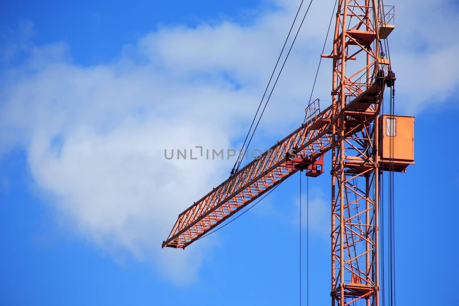 Industrial theme. Yellow construction crane against blue sky
