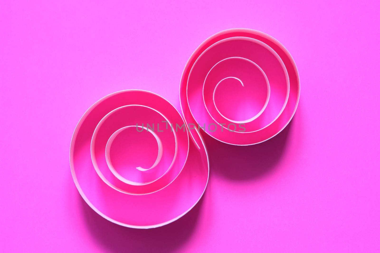 Abstract composition made from paper spirals on pink background