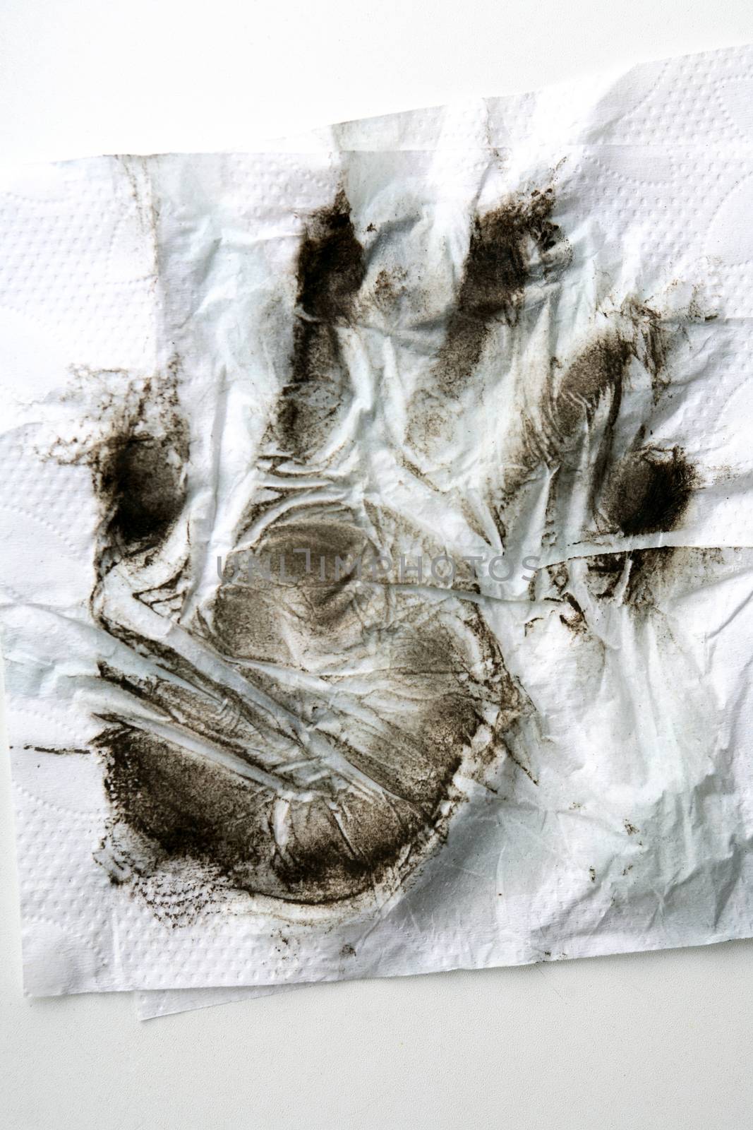 Black dirty handprint on white paper napkin