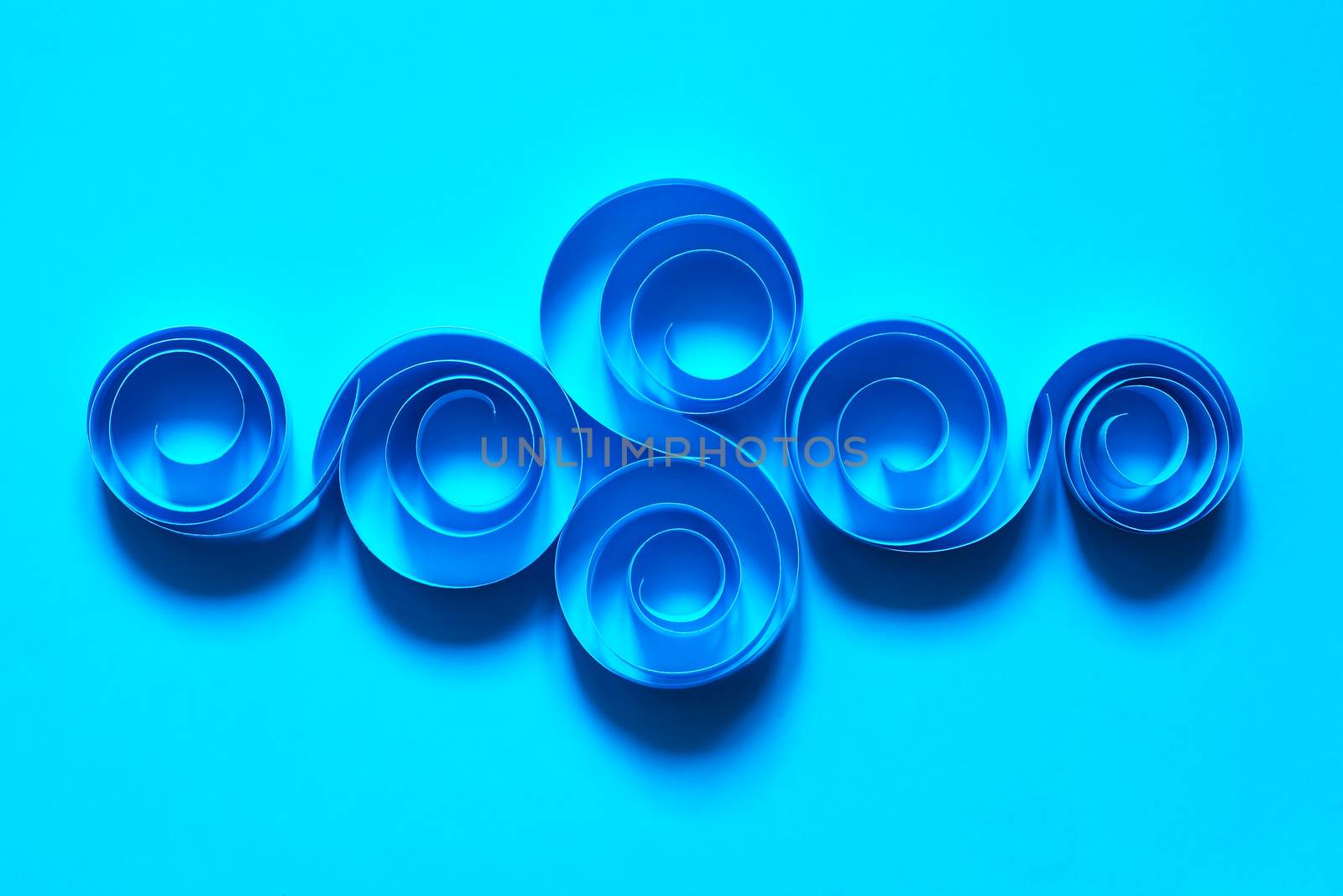 Abstract composition made from paper spirals on blue background