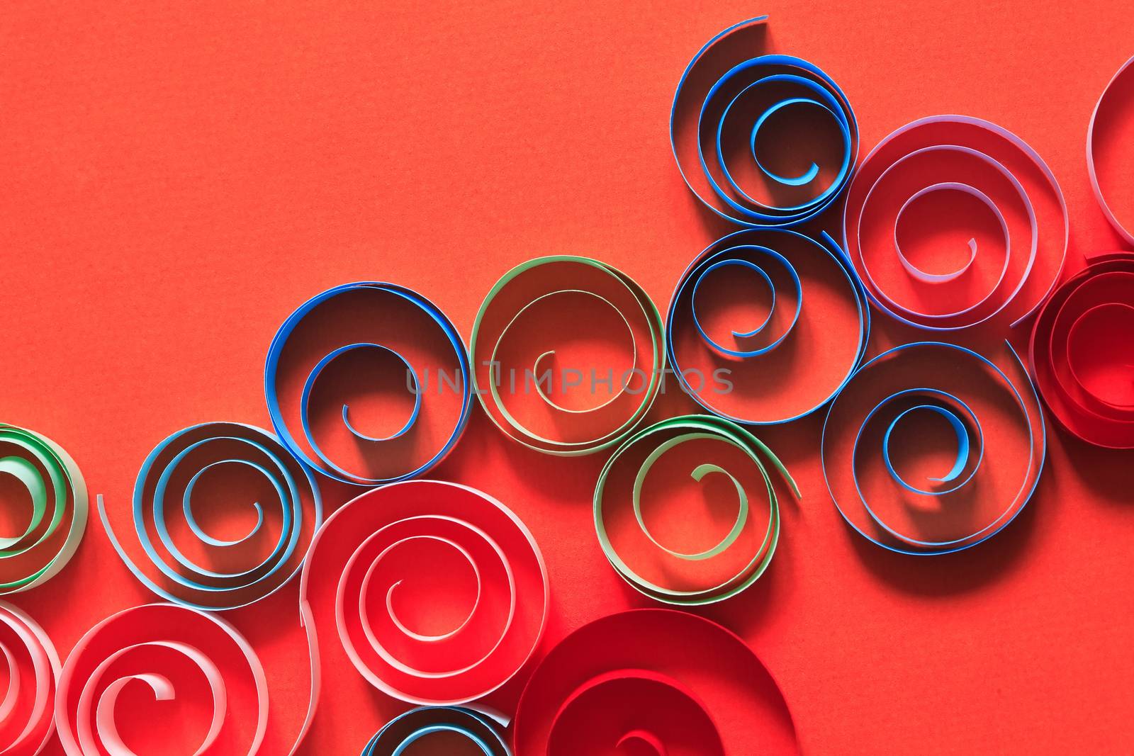 Multicolored spirals made from paper on red background