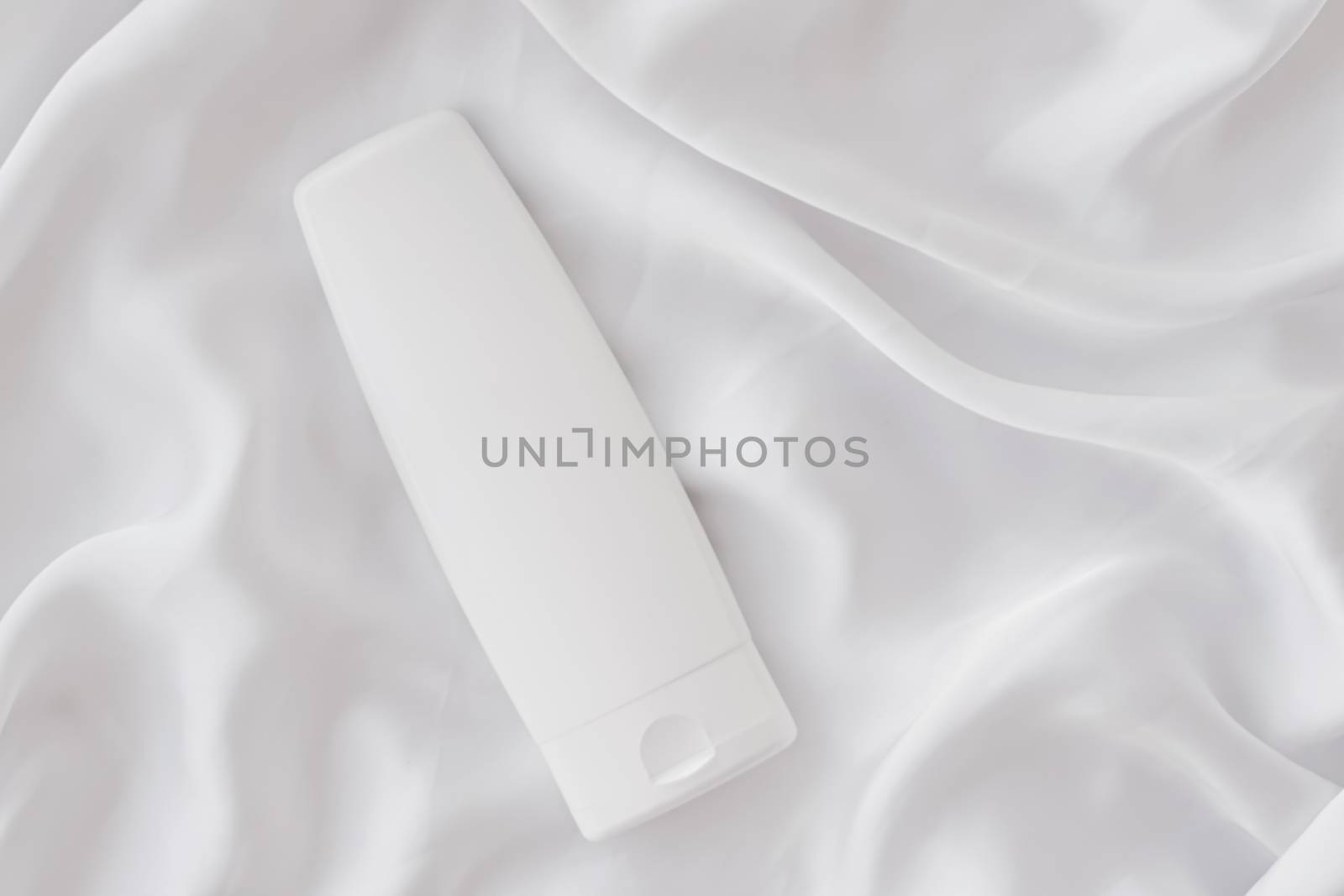 Blank label cosmetic container bottle as product mockup on white silk background by Anneleven