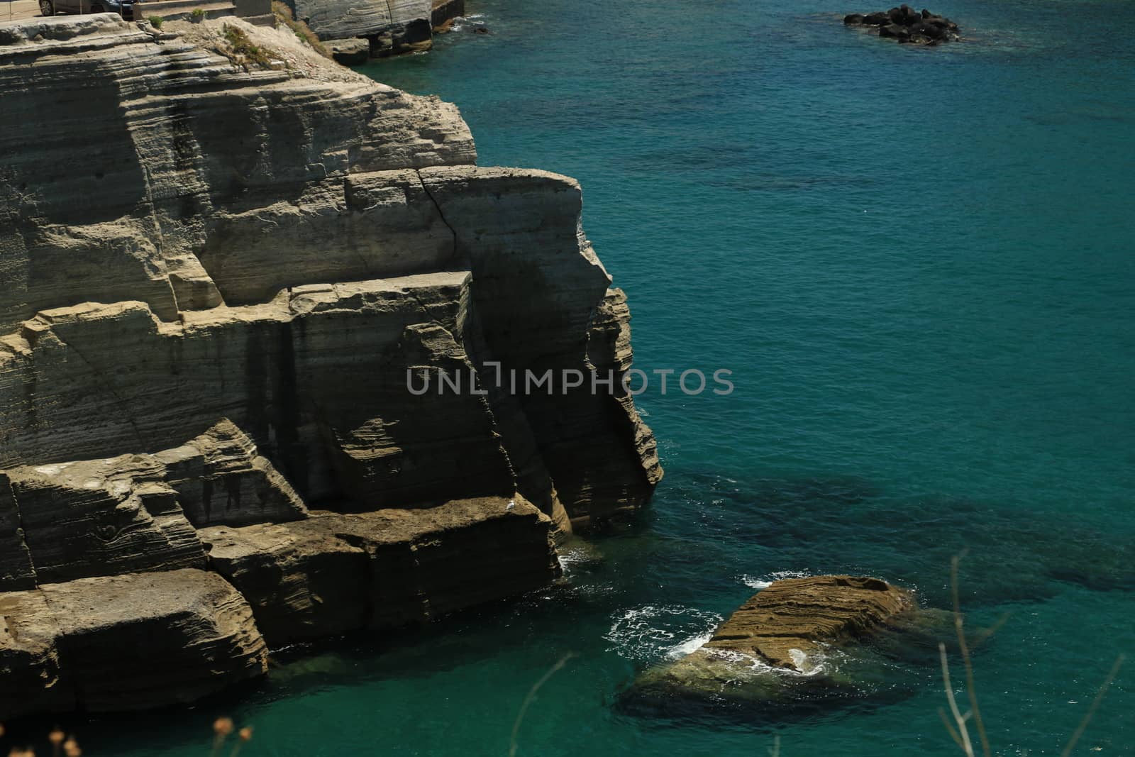 Volcanic rocks and rocks in the Mediterranean sea of Ischia. Close to Naples. The waves of the blue sea break on the cliff.