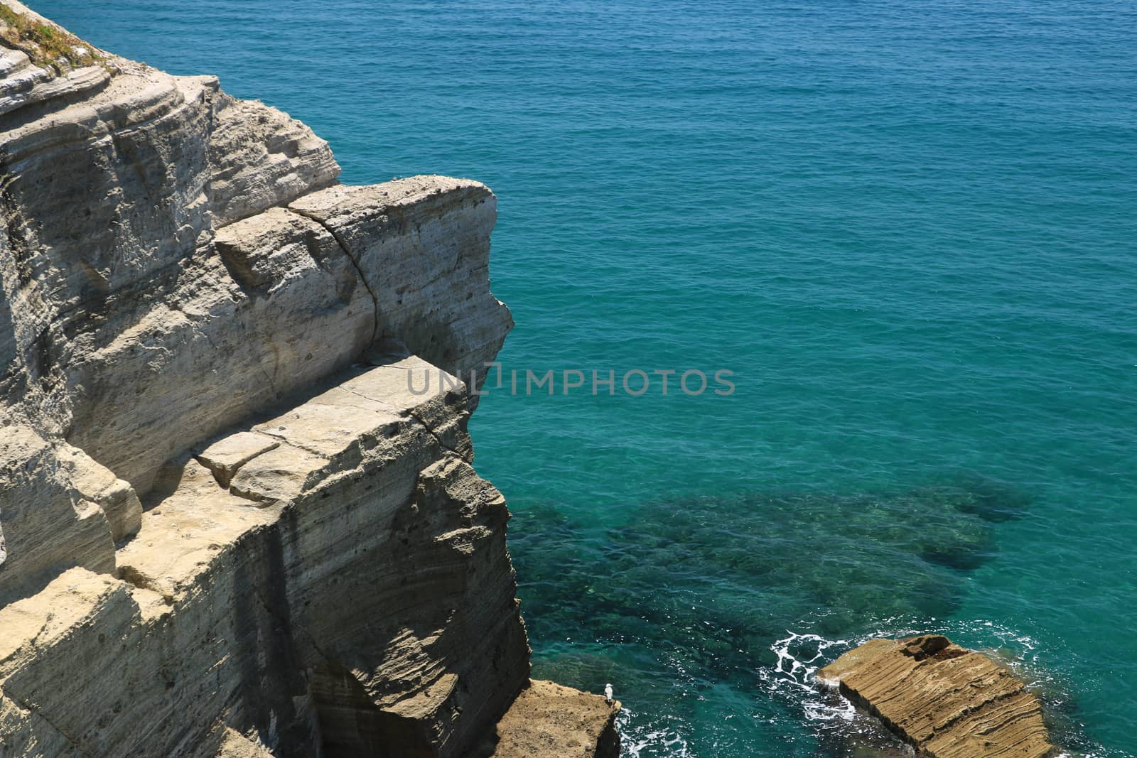 Volcanic rocks and rocks in the Mediterranean sea of Ischia. Close to Naples. The waves of the blue sea break on the cliff.