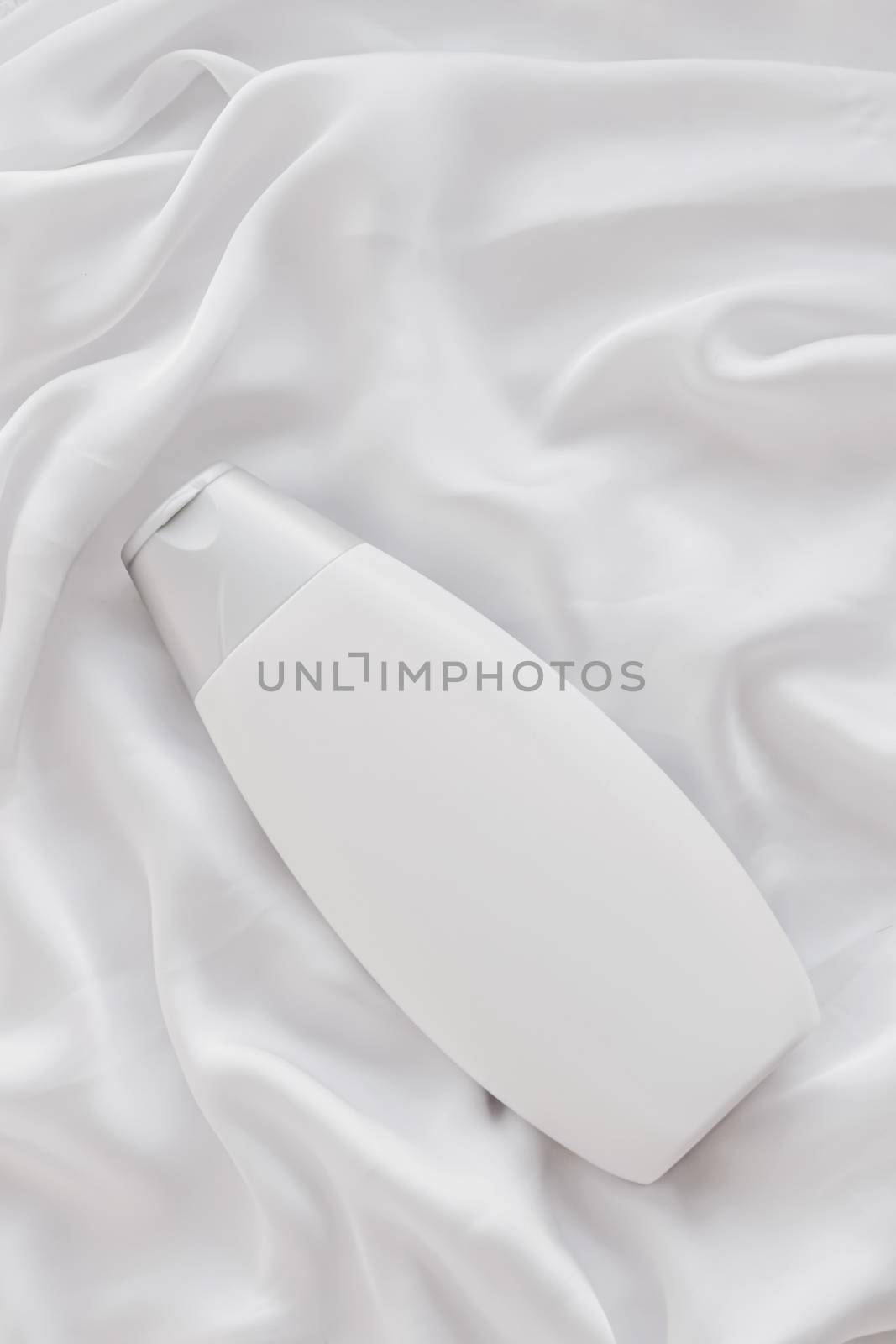 Blank label cosmetic container bottle as product mockup on white silk background by Anneleven