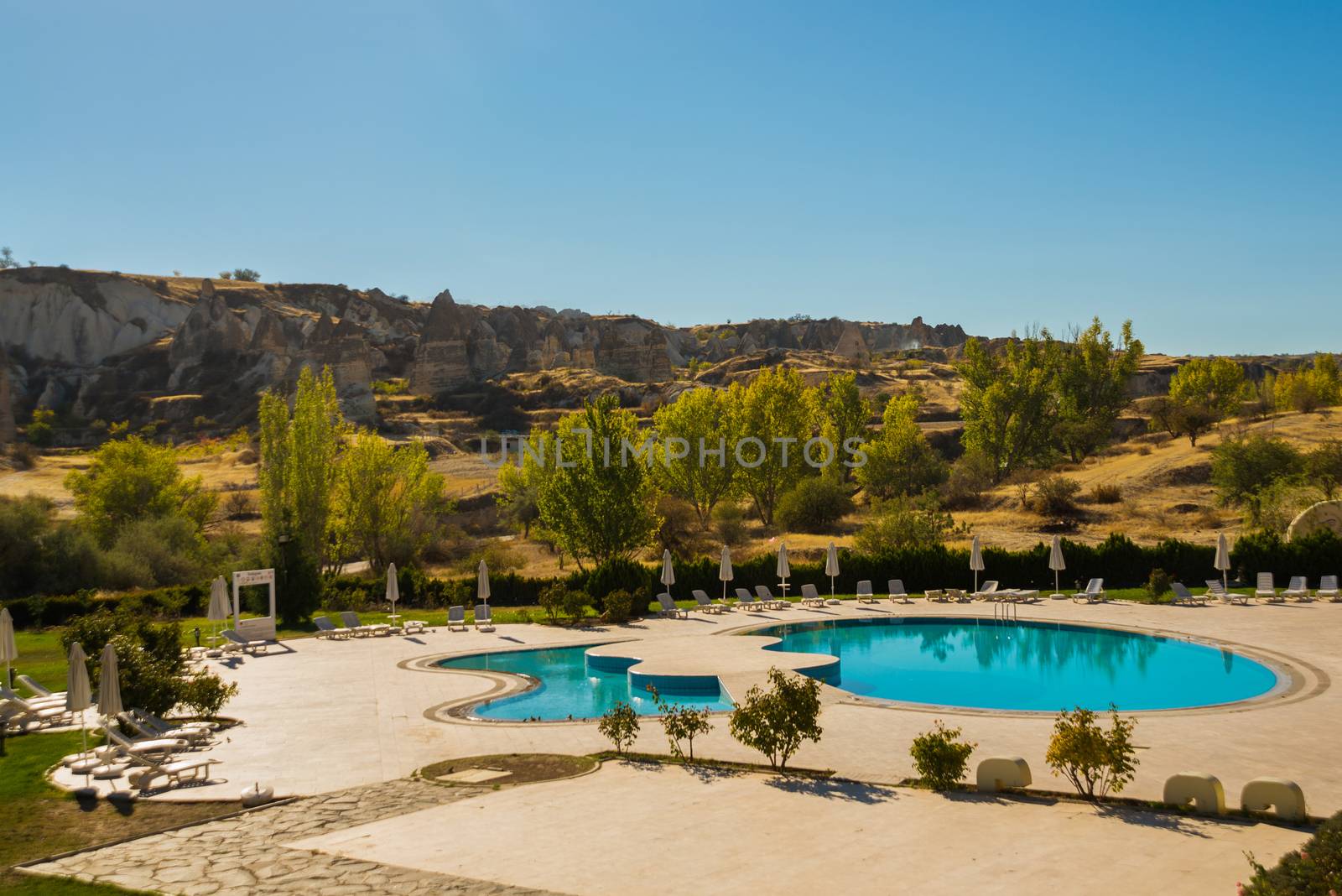 Beautiful landscape with mountains in the form of houses and a pool. Cappadocia, Anatolia, Turkey by Artamonova