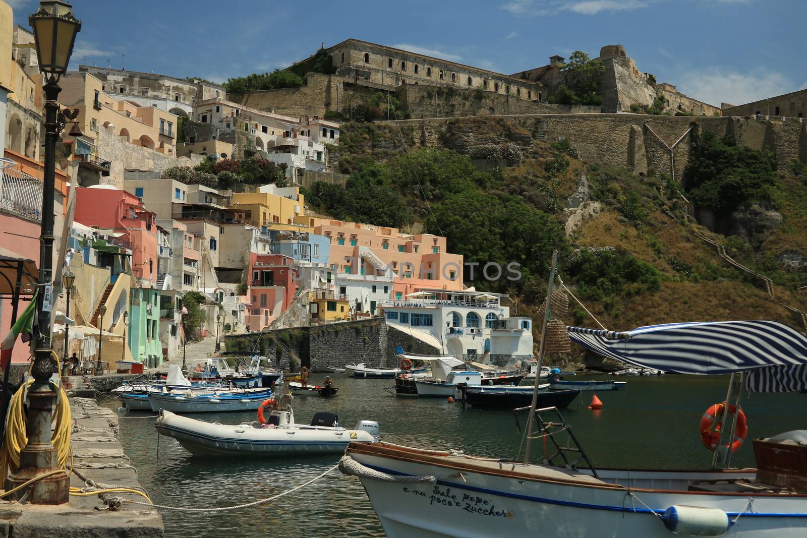 Procida island, Naples, Italy, About the July 2019. Boats anchored in the port of Corricella on the Island of Procida. Typical colorful Mediterranean style houses and fishing boats in the harbor.