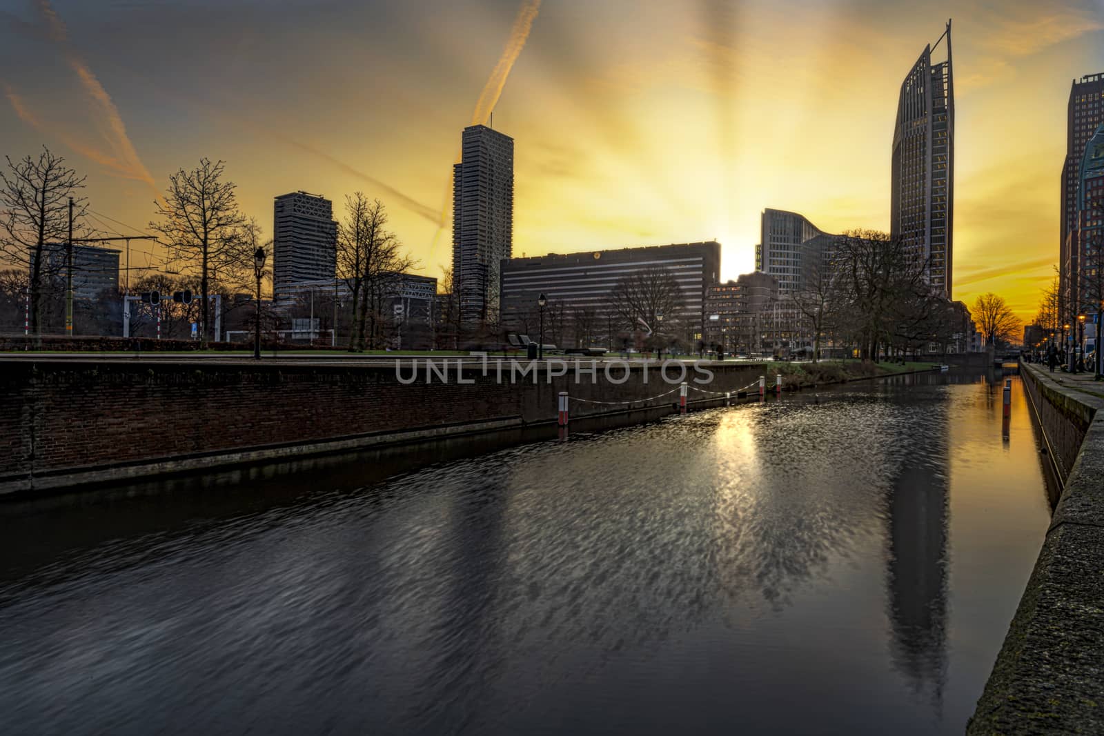 View of The Hague sunrise, early morning skyline reflected on the calm canal's water, Netherlands