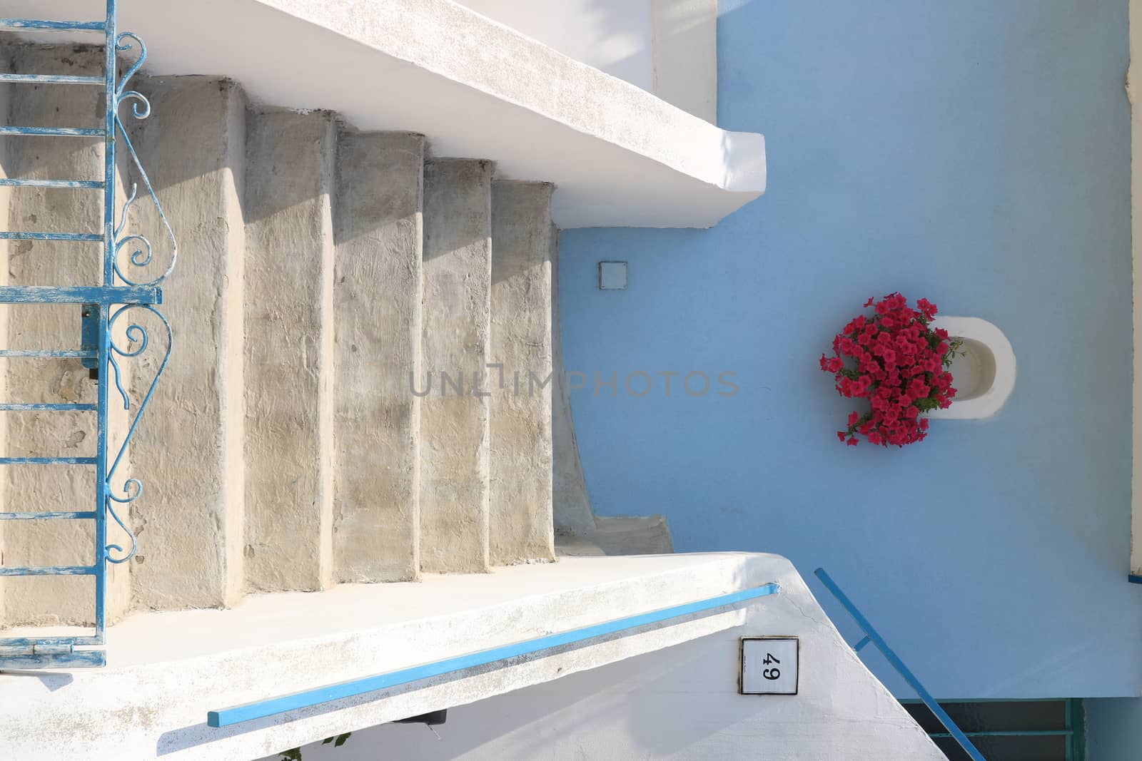 Procida island, Naples, Italy, About the July 2019. Vase of red flowers on Mediterranean house facade. Staircase with handrail and number plate