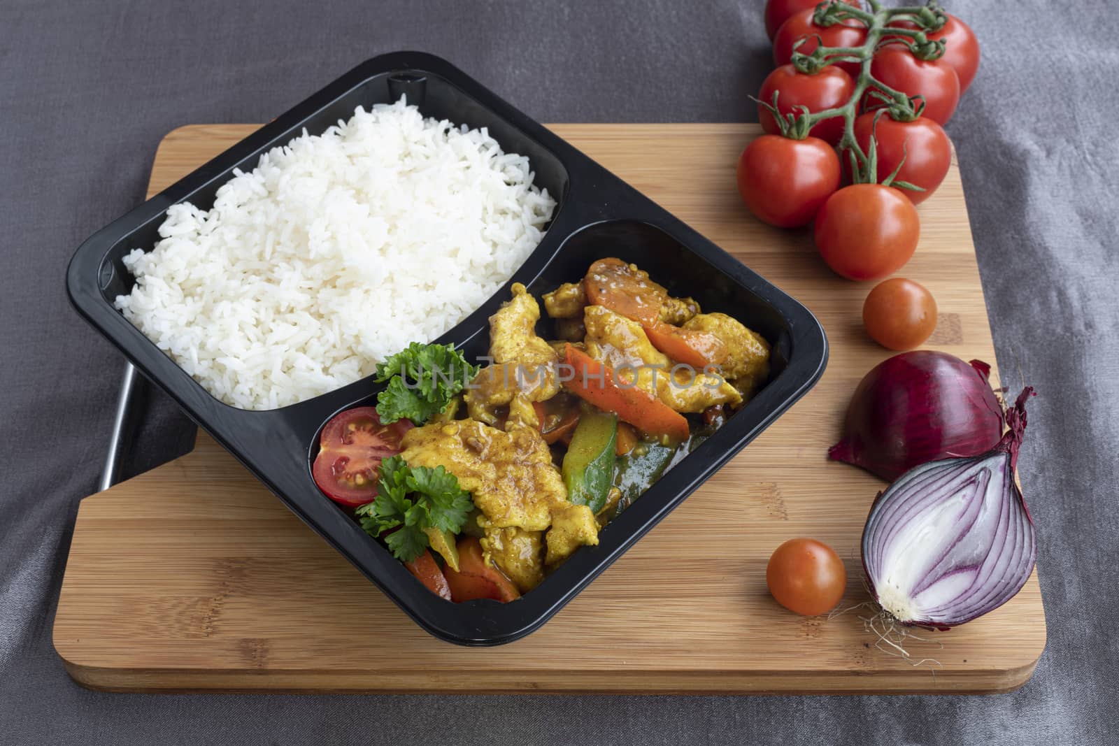 Box of stir fried chicken curry noodle served with white rice in a packaging recipient for take away