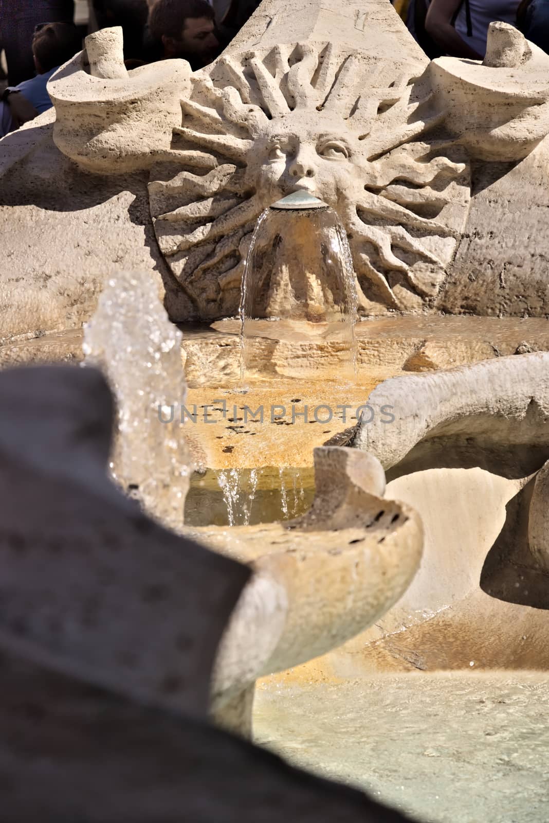 Barcaccia Fountain in Piazza di Spagna in Rome. Rome Italy. 05/02/2019.  Detail of a sun-shaped mouth with a human face from which water flows. Pietro Bernini project.