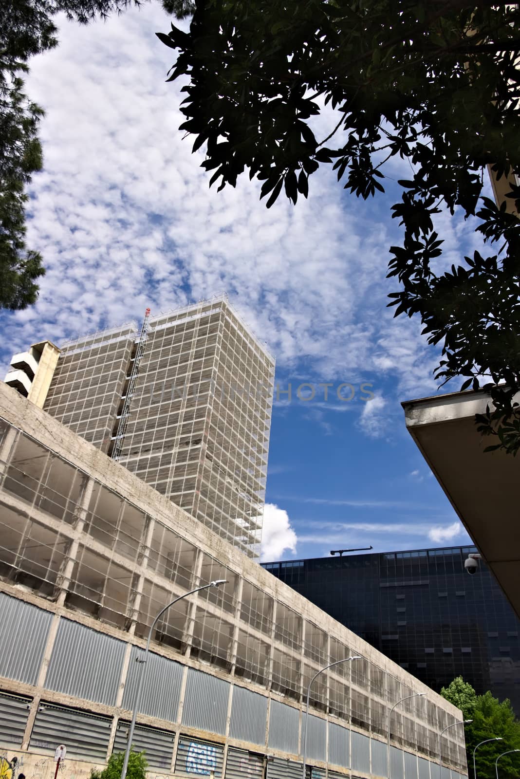 Restructuring of an office building. Rome Eur, Italy. 05/03/2019. Complex of buildings under renovation with the construction of new facades. Blue sky with clouds.