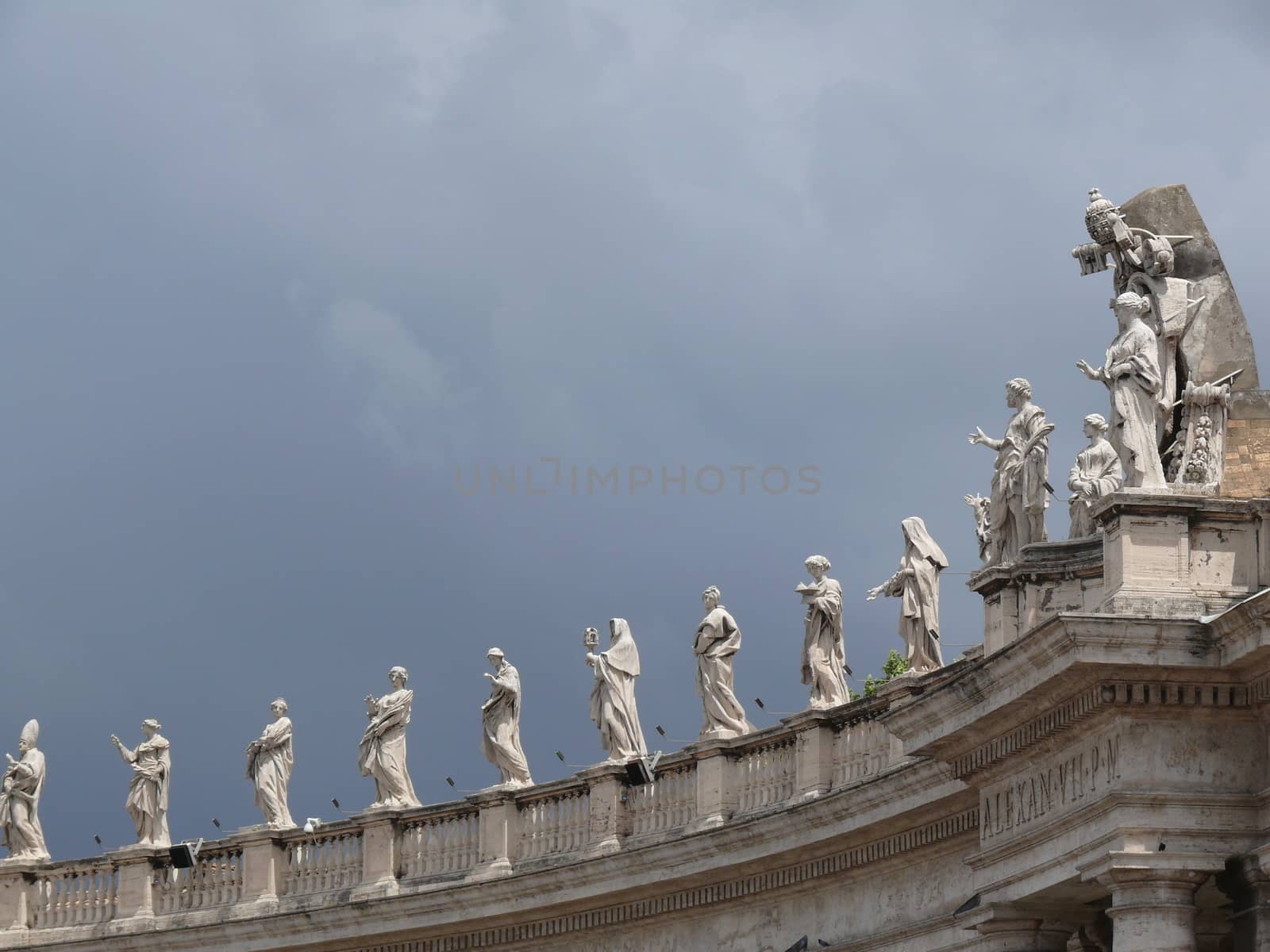 Cloudy sky over the statues of the colonnade of St. Peter's Square in the Vatican.