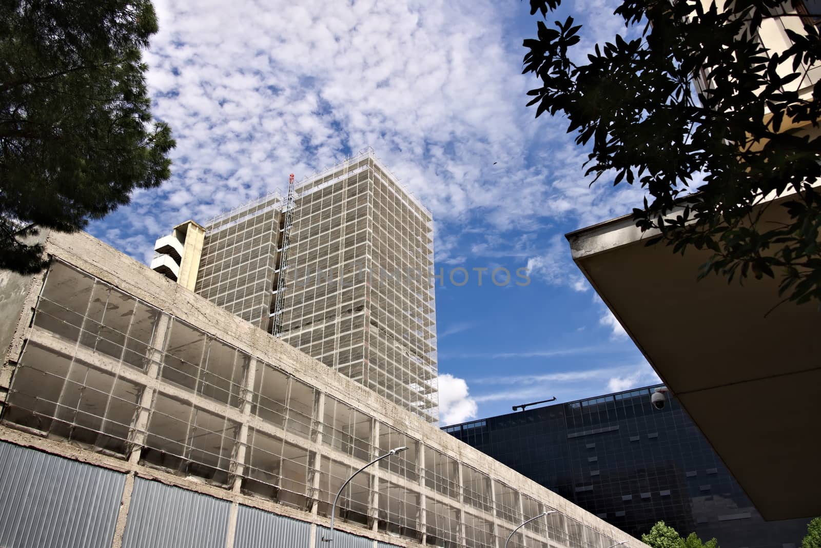 Restructuring of an office building. Complex of buildings under renovation with the construction of new facades. Blue sky with clouds.