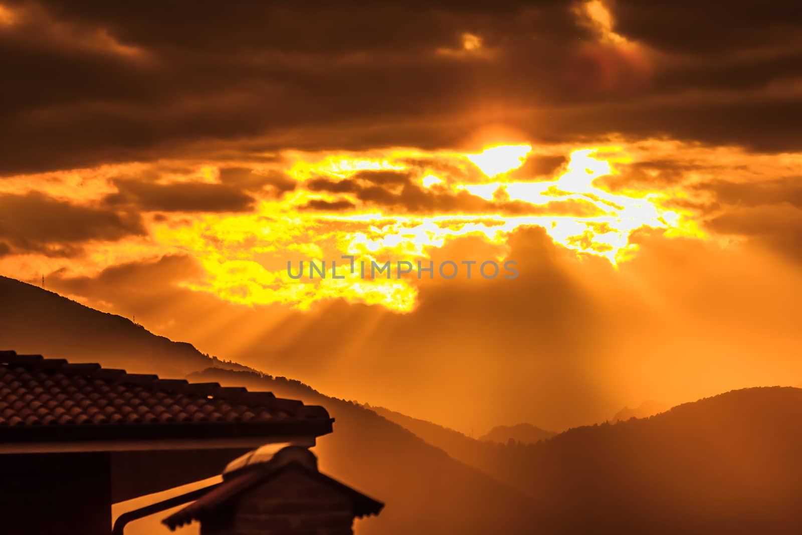 a landscape made magical by blurry  roofs and mountains lit by the setting sun