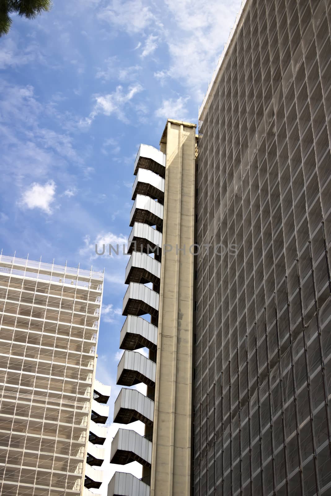 Restructuring of an office building. Complex of buildings under renovation with the construction of new facades. Blue sky with clouds.