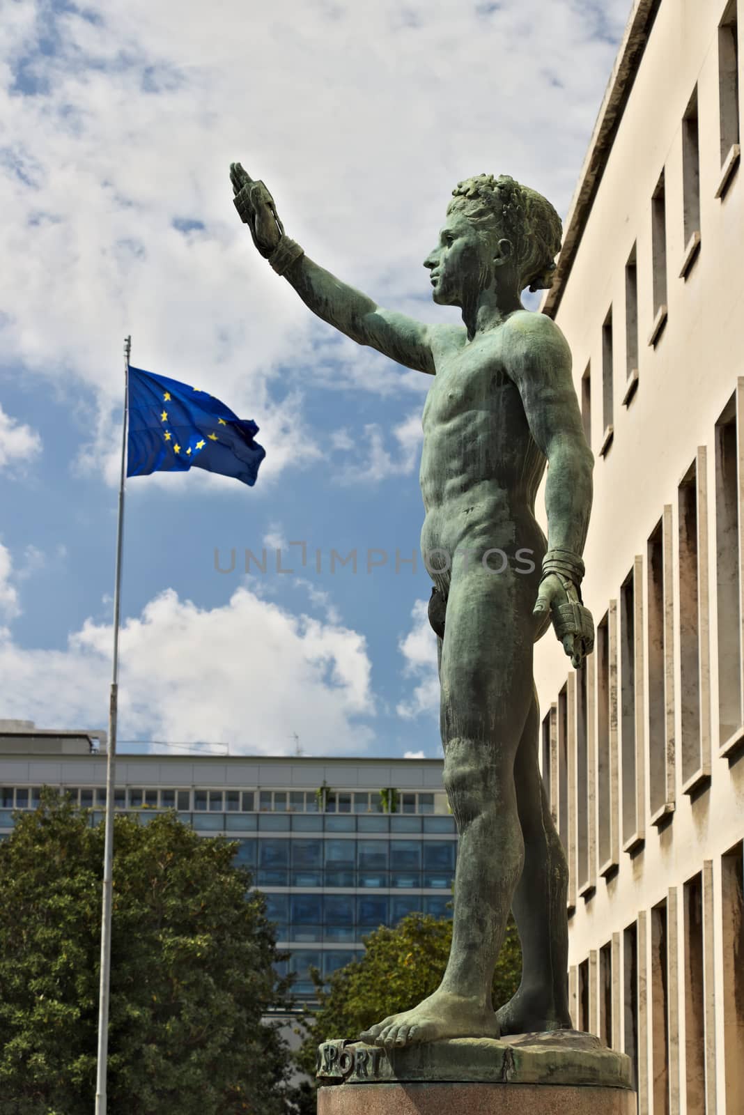 Bronze statue of the Sports Genius in the EUR, Rome and European flag. Rome Eur, Italy. 05/03/2019. Sculpture by Italo Griselli depicting a sportsman with a fascist salute. The European flag is flying in the background.