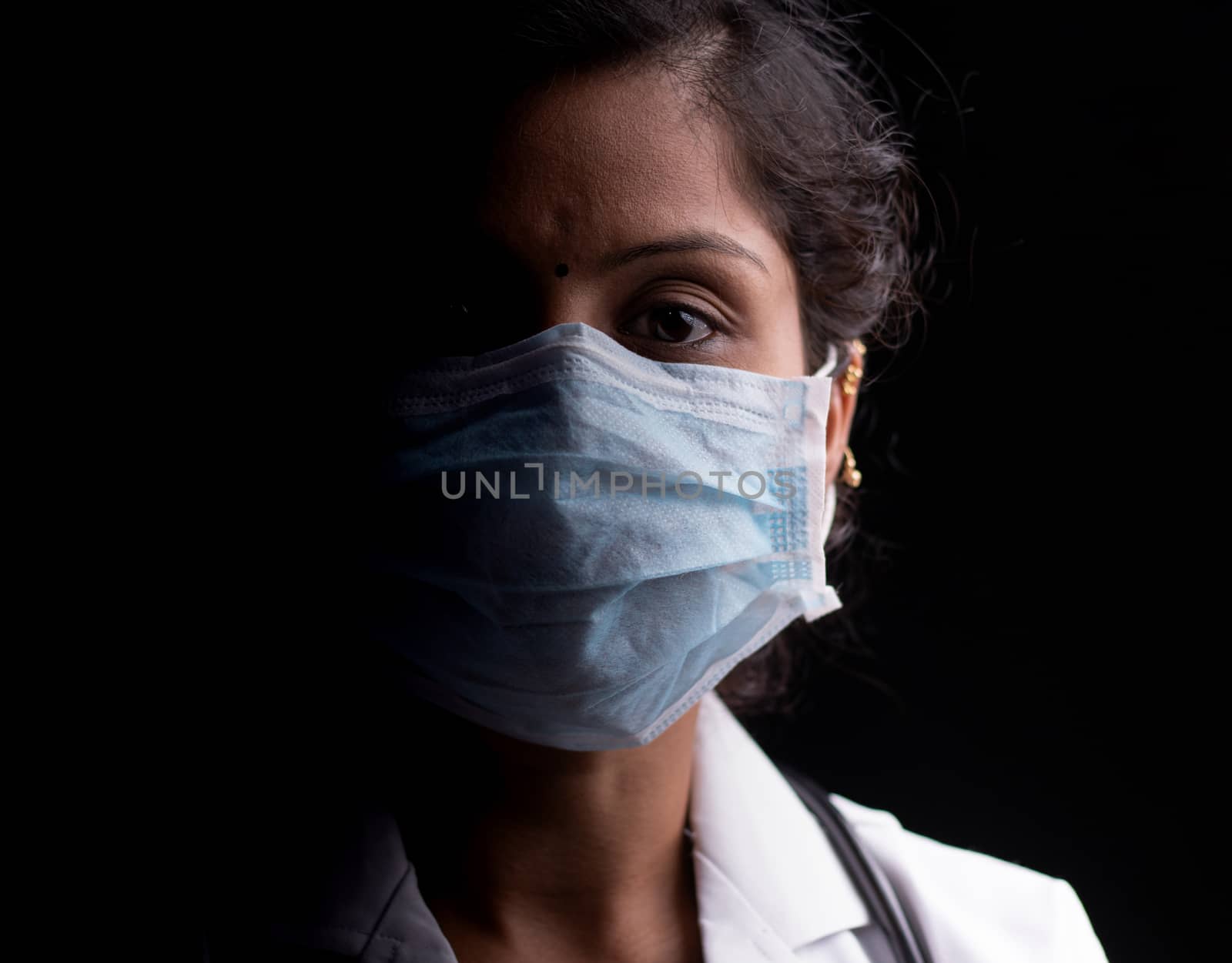 Close up of professional Medical doctor or nurse protective medical facial mask in dark room - Concept of covid-19 pandemic hope concept. by lakshmiprasad.maski@gmai.com