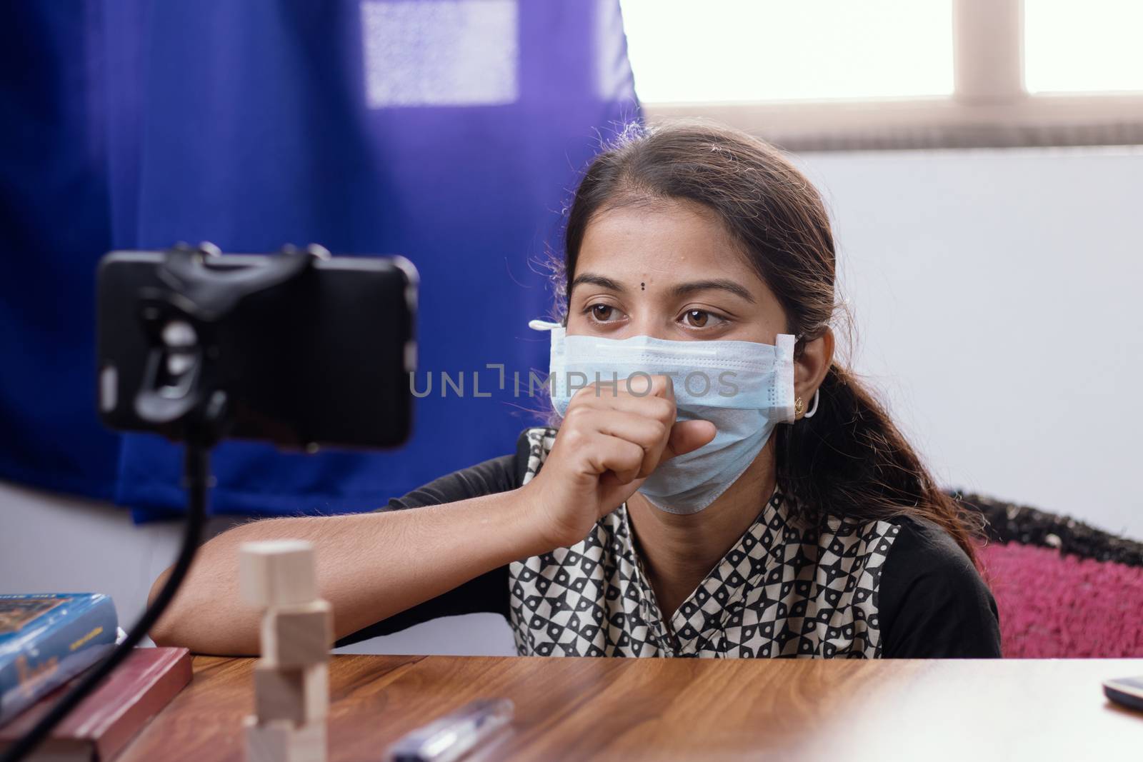 Young Girl in medical face mask talking or having chat with doctor in video conference on mobile phone - telehealth, telemedicine or tele counseling Doctor during coronavirus or covid-19 Crisis