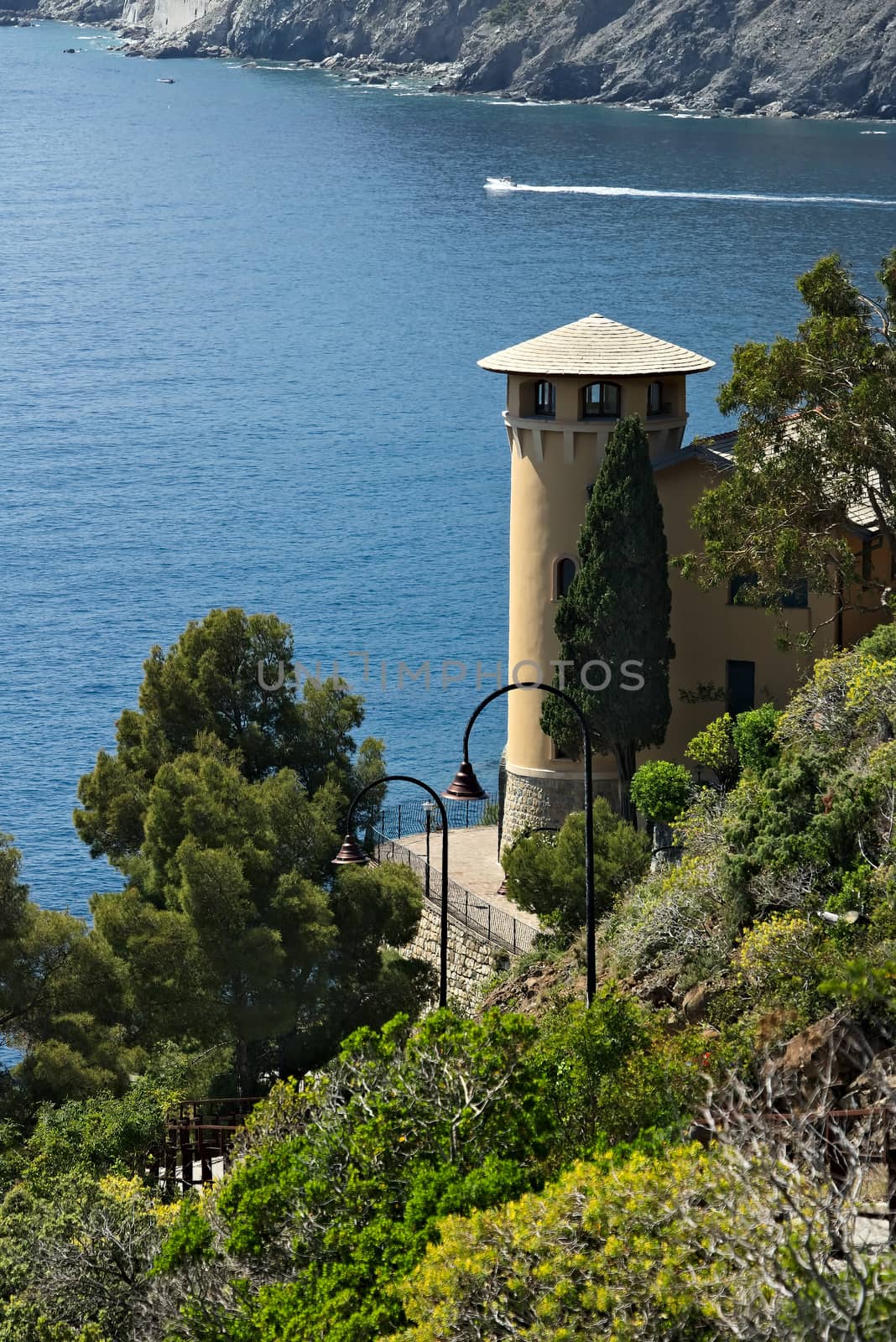 Seascape with house turret near the Cinque Terre. In the village of Framura a villa with a tower overlooking the blue sea and dense Mediterranean vegetation.