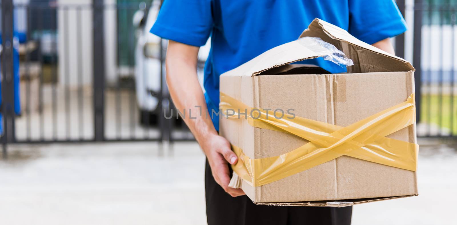 Asian young delivery man in blue uniform he emotional falling courier hold damaged cardboard box is broken at door front home, Accident bad transport shipment or poor quality delivery service concept