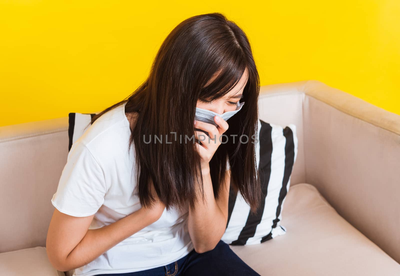 Woman sitting on sofa wearing protection face mask hygiene again by Sorapop