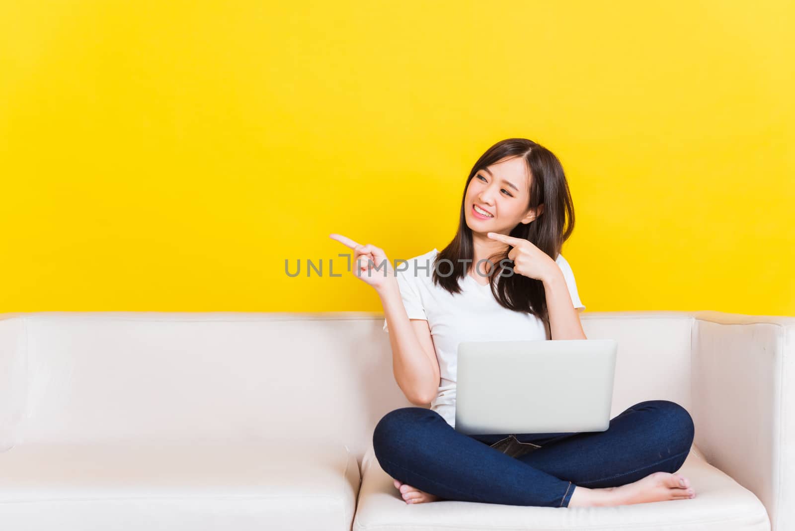 Woman work from home she sitting on sofa using laptop computer i by Sorapop