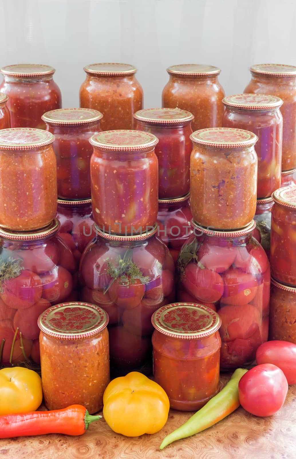 In glass jars Lecho of canned bell peppers and tomatoes, adjika, canned tomatoes, near fresh peppers and tomatoes