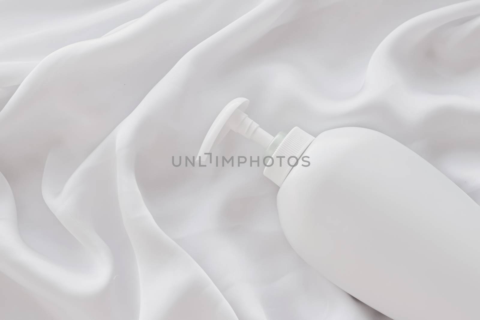 Blank label cosmetic container bottle as product mockup on white silk background by Anneleven