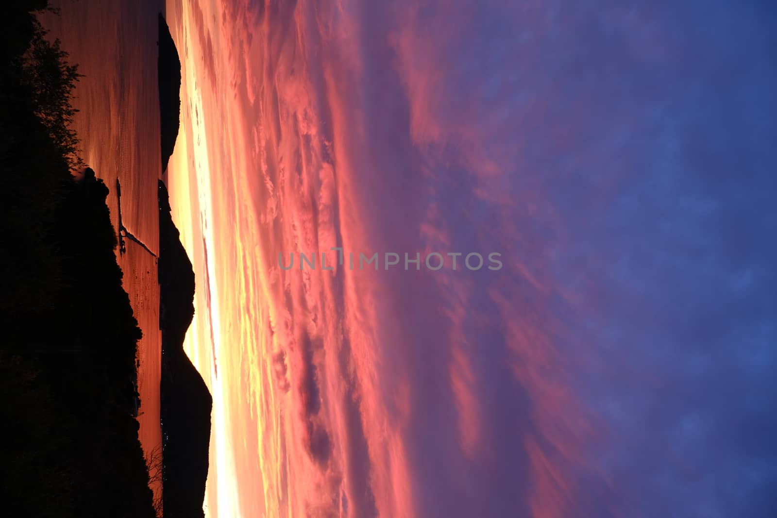 Sun setting over the sea with red and blue clouds. Gulf of La Spezia, Mediterranean Sea in Liguria.