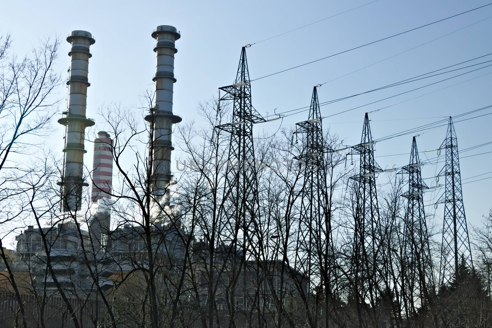 The Turbigo power plant, 40 km from Milan, owned by Iren is located along the Naviglio Grande. The video shows steam puffs coming out of the central, behind the tall chimneys.  The shot goes from the chimneys and pylons to the view of the dry river bed of the Naviglio that flows nearby.