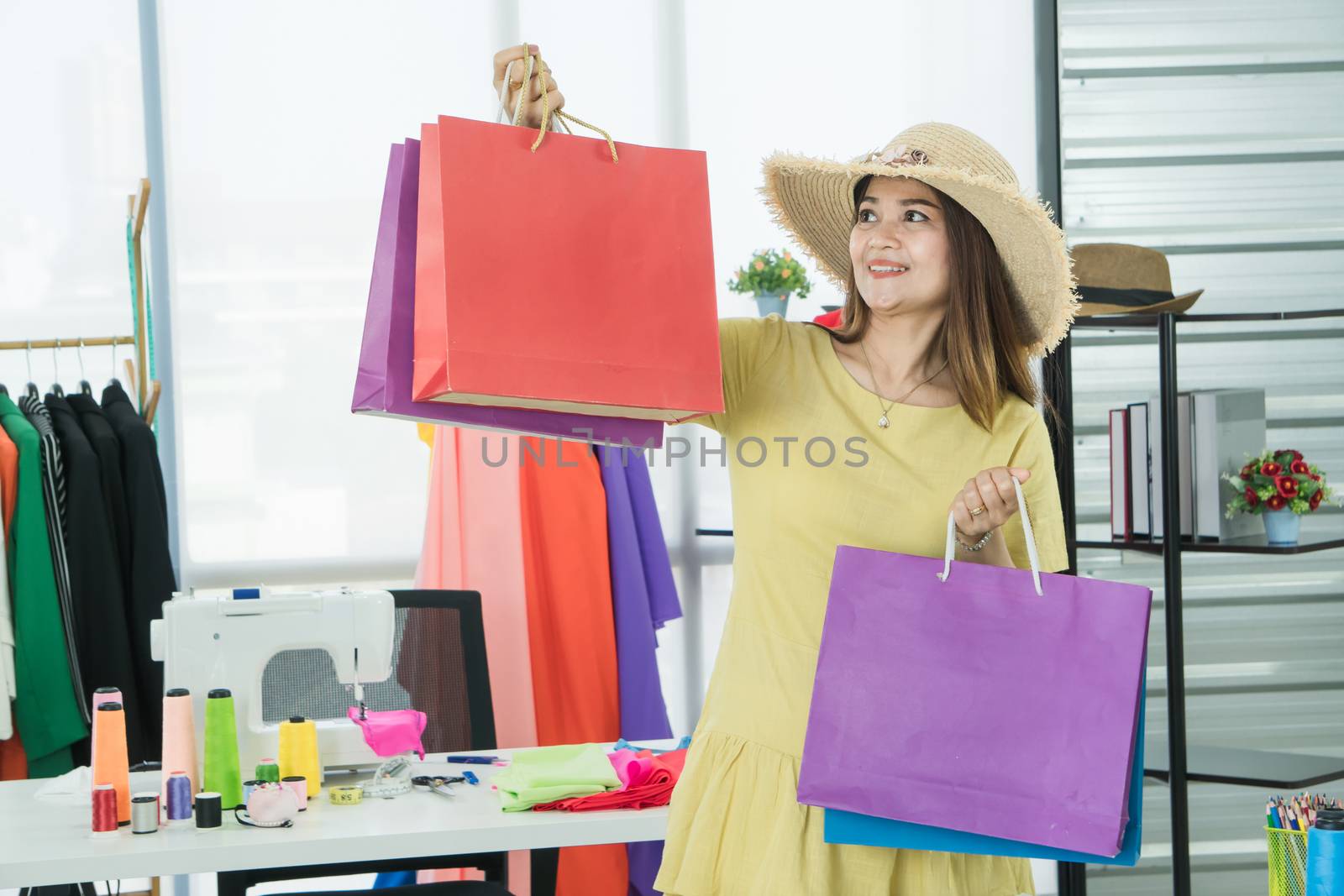 A senior female fashion designer from Asia is working in a textile factory. Confidently with starting a new business And smile at the camera friendly